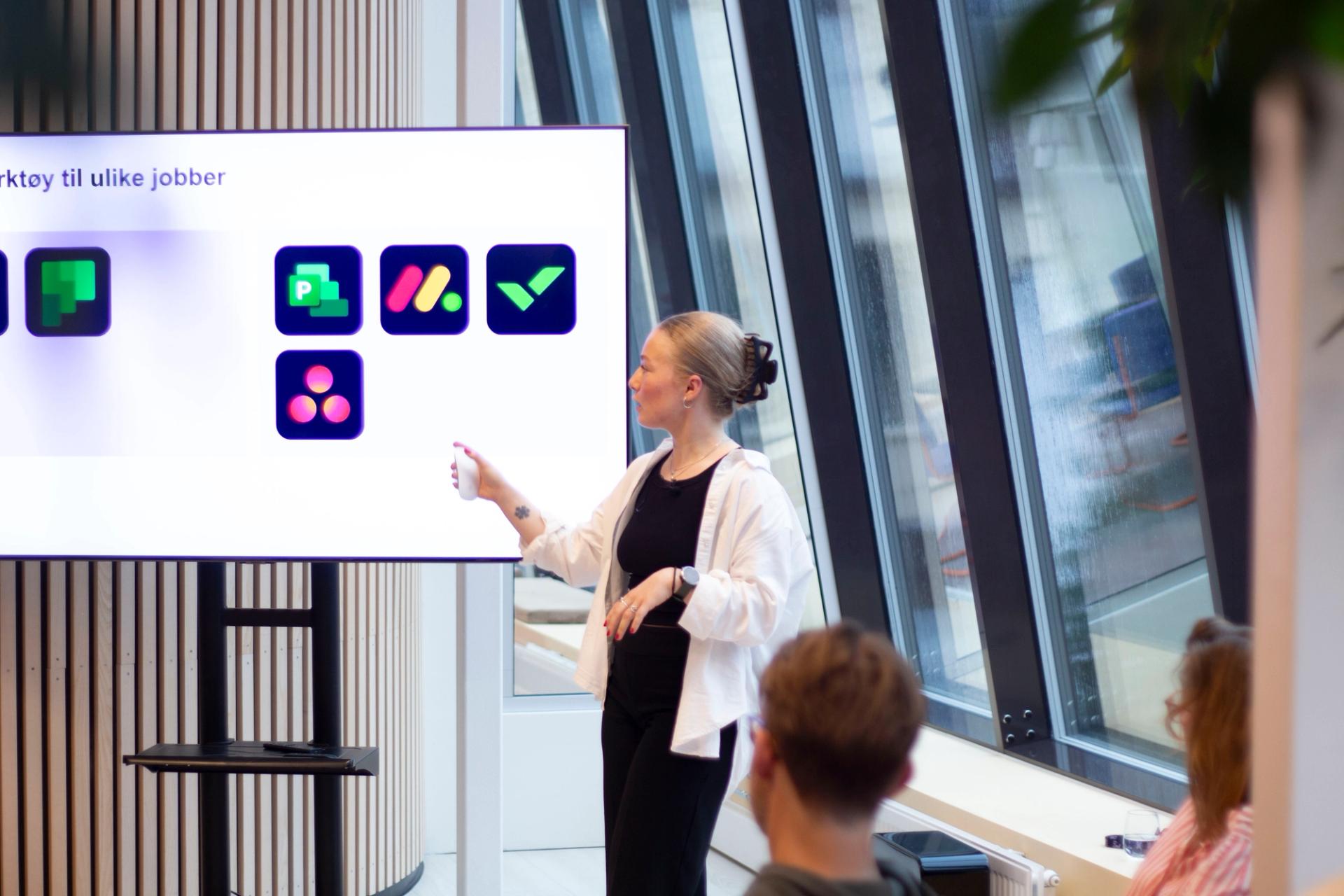 En kvinne presenterer verktøy for oppgavestyring på en skjerm til et publikum.