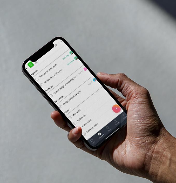 En hånd holder en smarttelefon som viser en liste med oppgaver, inkludert "progress on team goals" og "design team offsite plan".