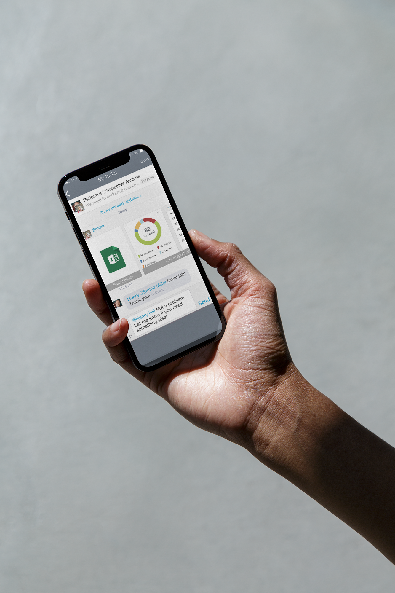En person holder en smarttelefon som viser en prosjektstyringsapp med en oppgave, en sirkeldiagram og meldinger.