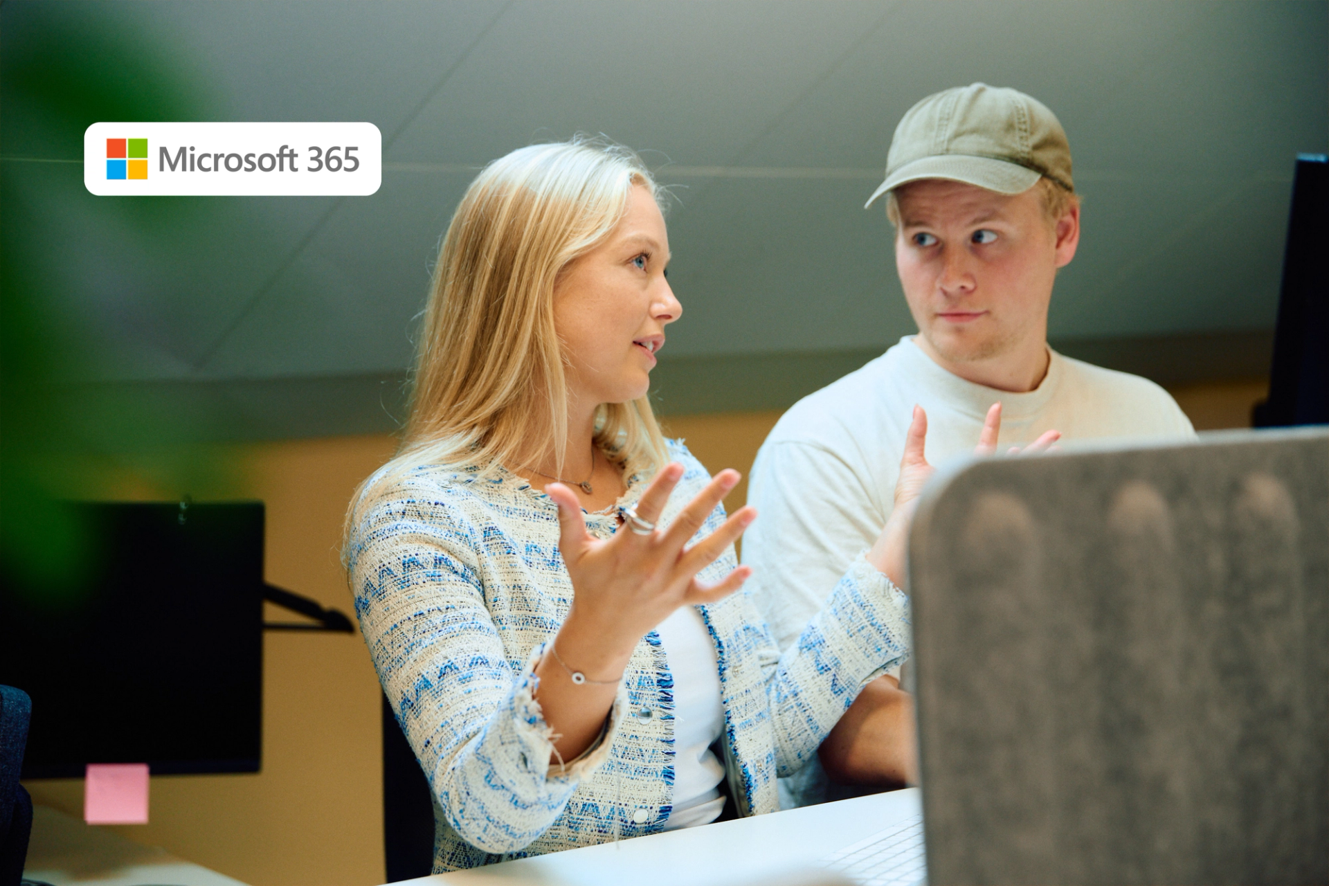 En kvinne og en mann snakker på et kontor, med Microsoft 365-logoen øverst til venstre.