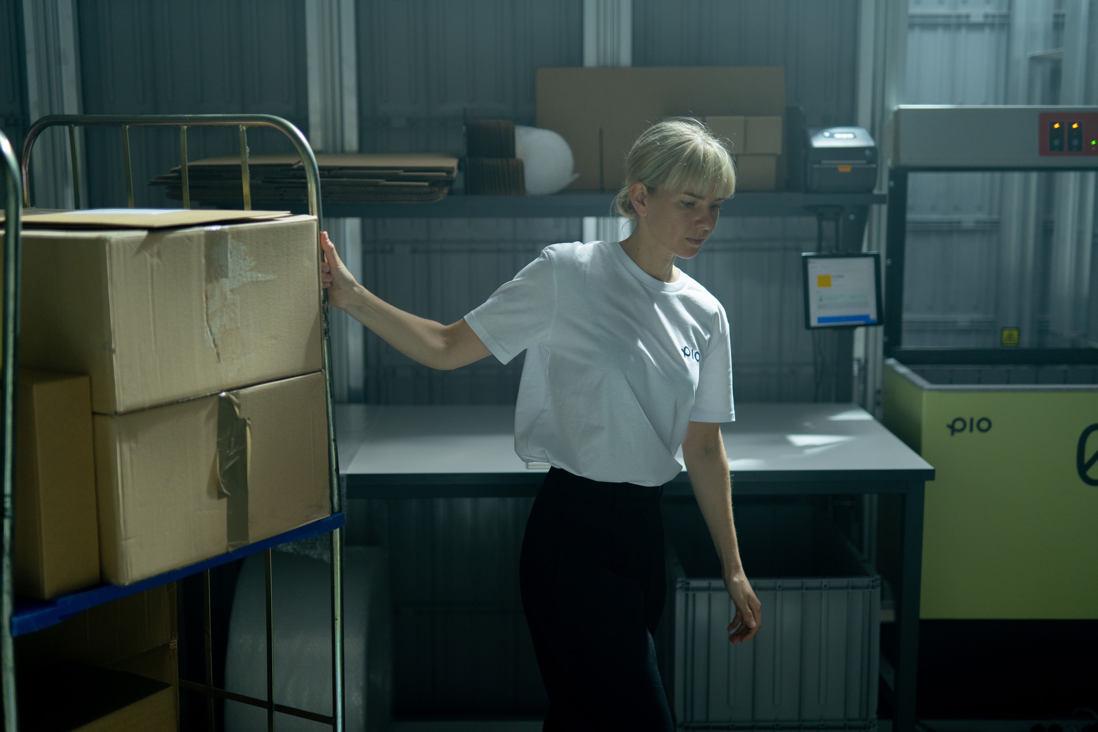 A woman working in a warehouse handling a cart full of packages.