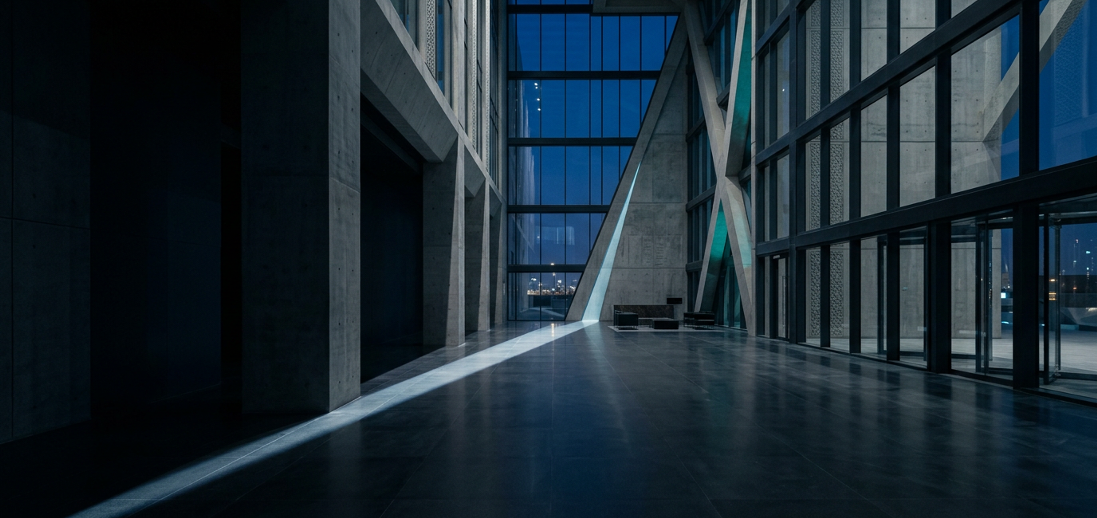 A minimal headquarters atrium at blue hour, a single beam of cool light across the polished stone floor.