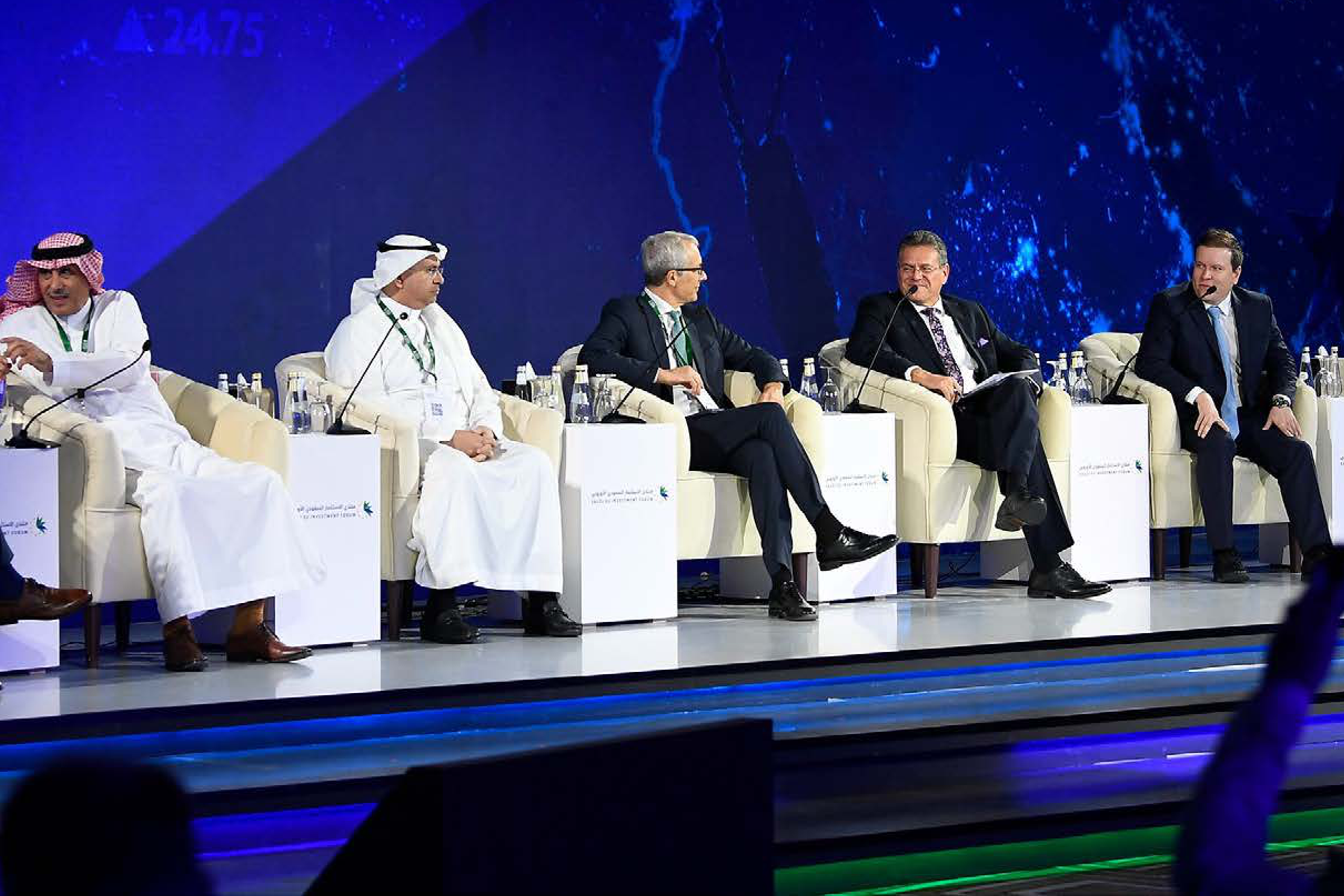 Panel discussion on stage at the Saudi-EU Investment Forum, with speakers seated in front of a large screen.
