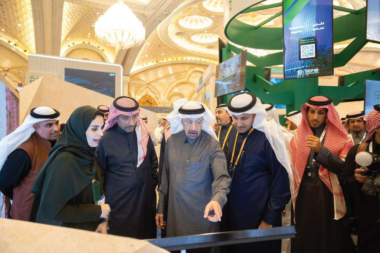 Officials gathered around a display at the Future Minerals Forum, with one pointing at the exhibit.