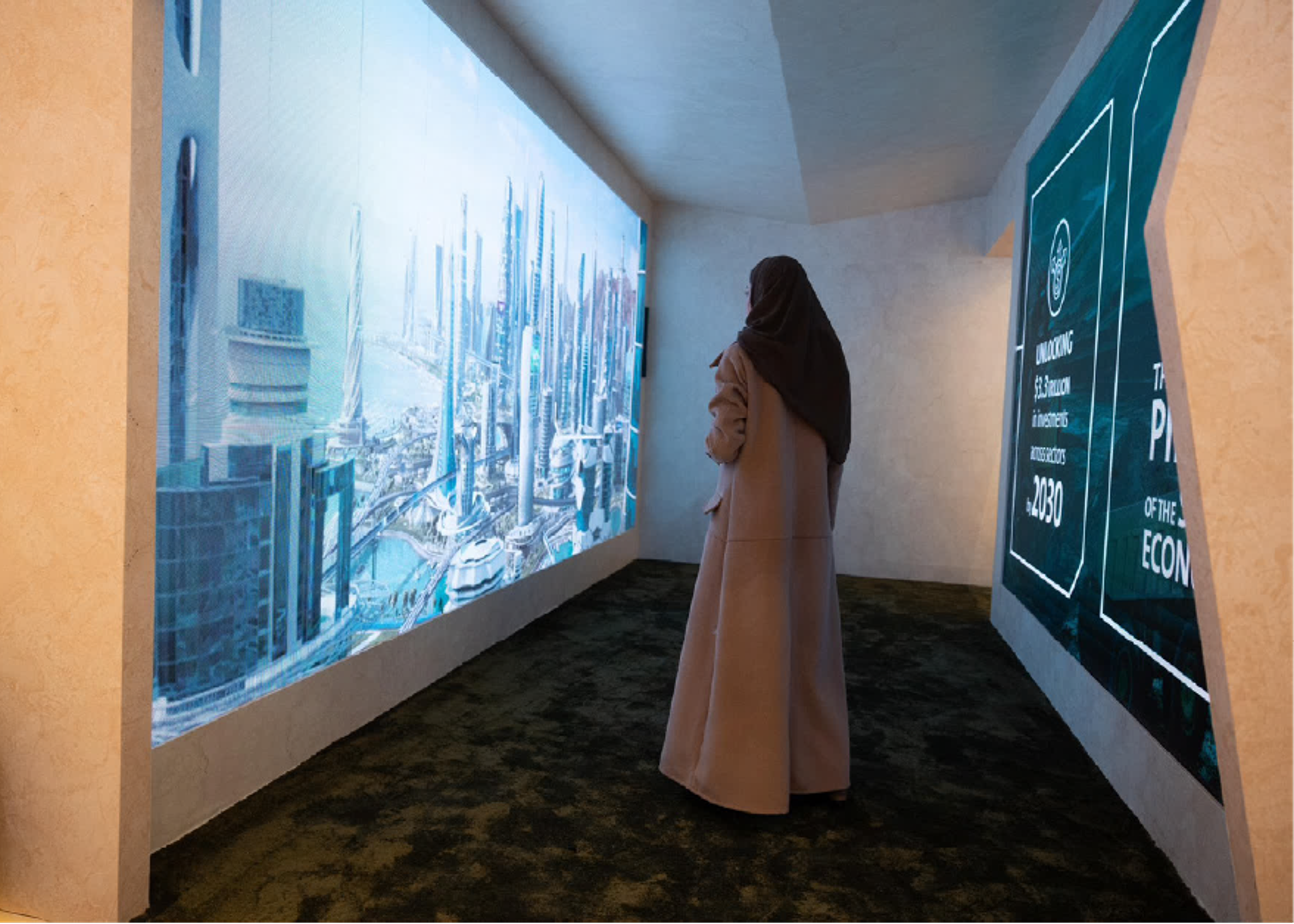 A woman stands in a darkened exhibition room, facing a wall-sized projection of a futuristic city skyline.