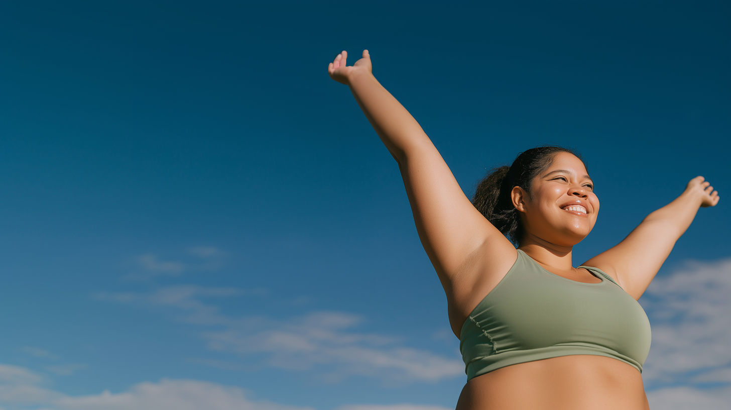 Smiling woman stretching her arms overhead against a blue sky