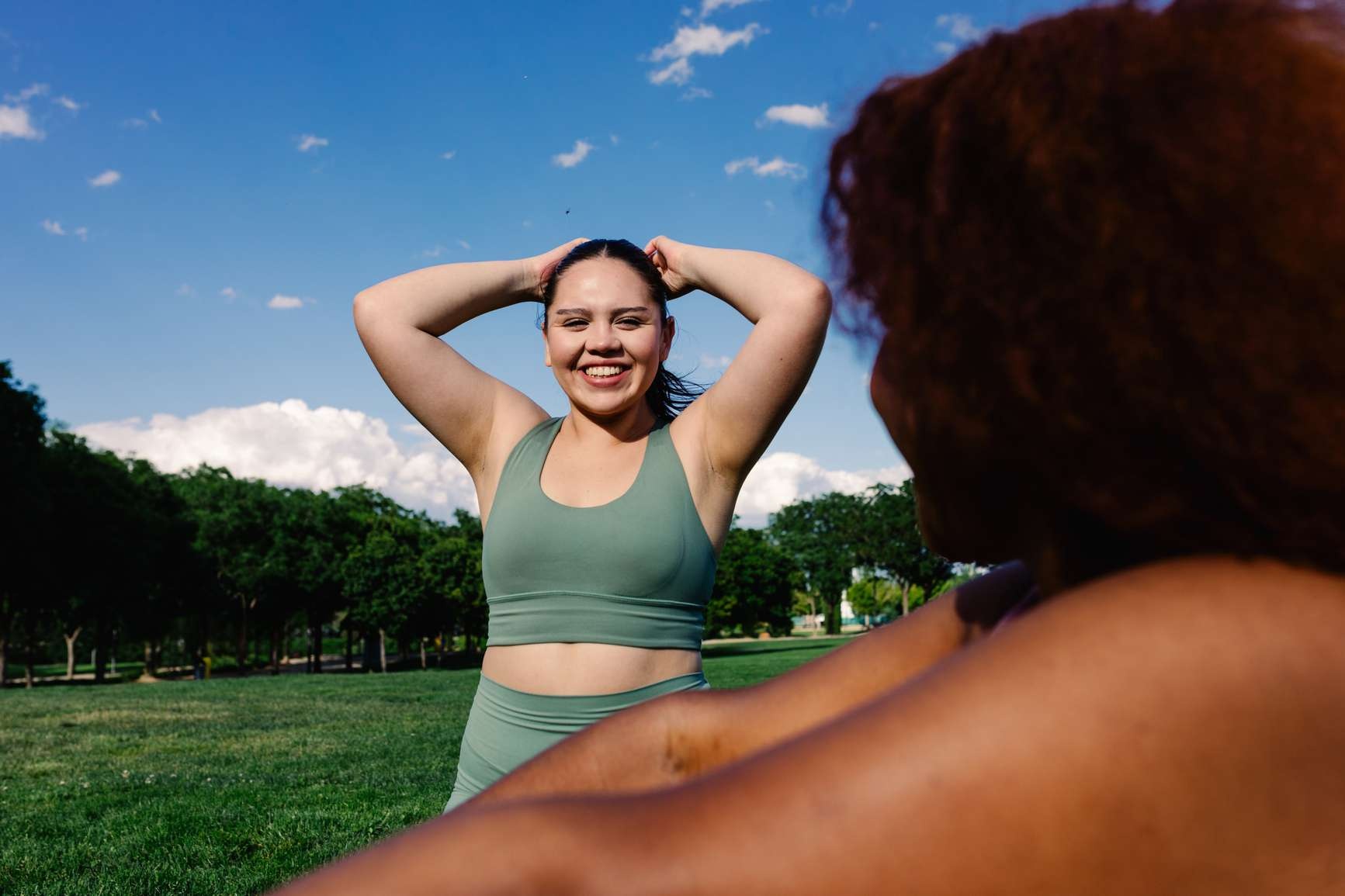 Smiling woman with her hands behind her head in a sunny park