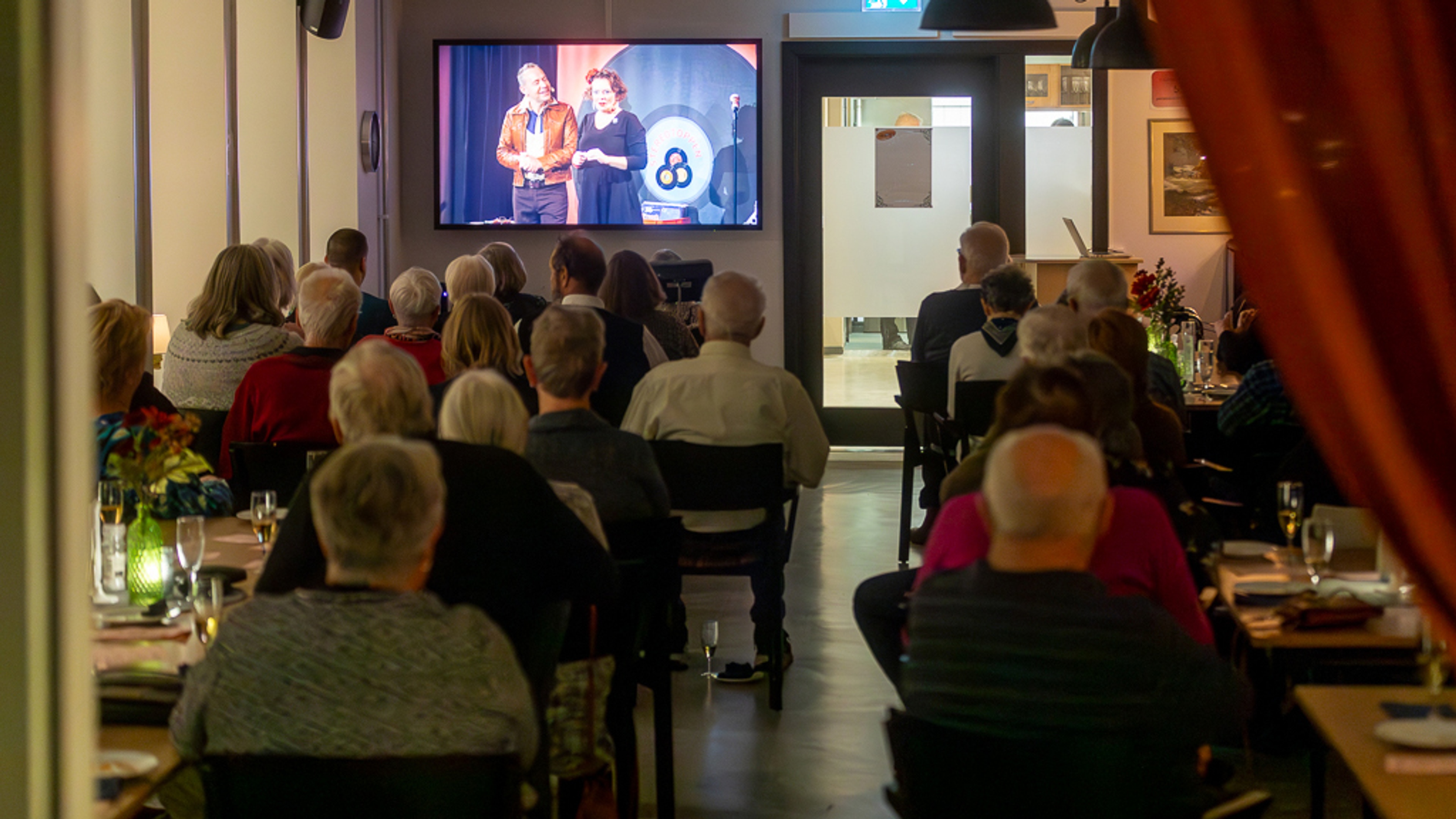 En samling människor njuter av snittar och digital scenkonst