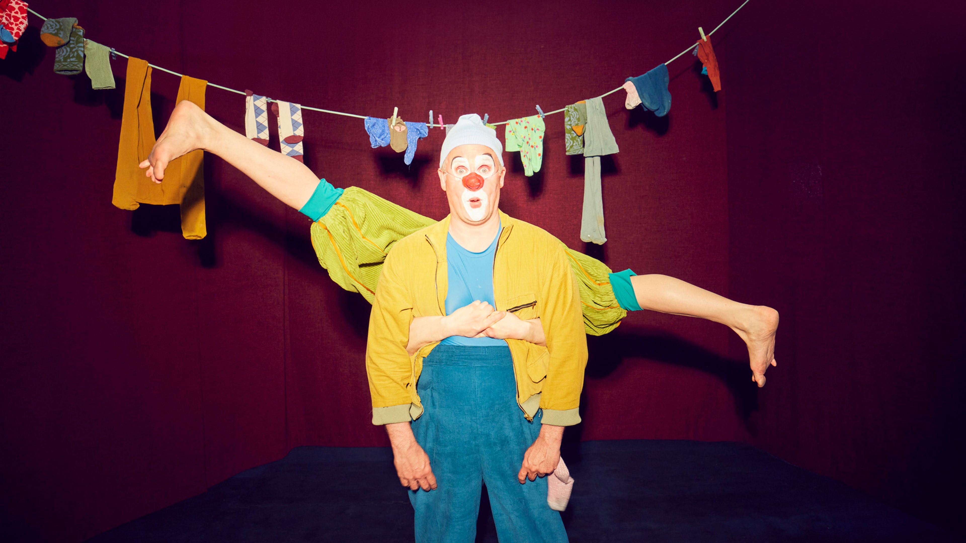 Två clowner framför en tvättlina med strumpor. 