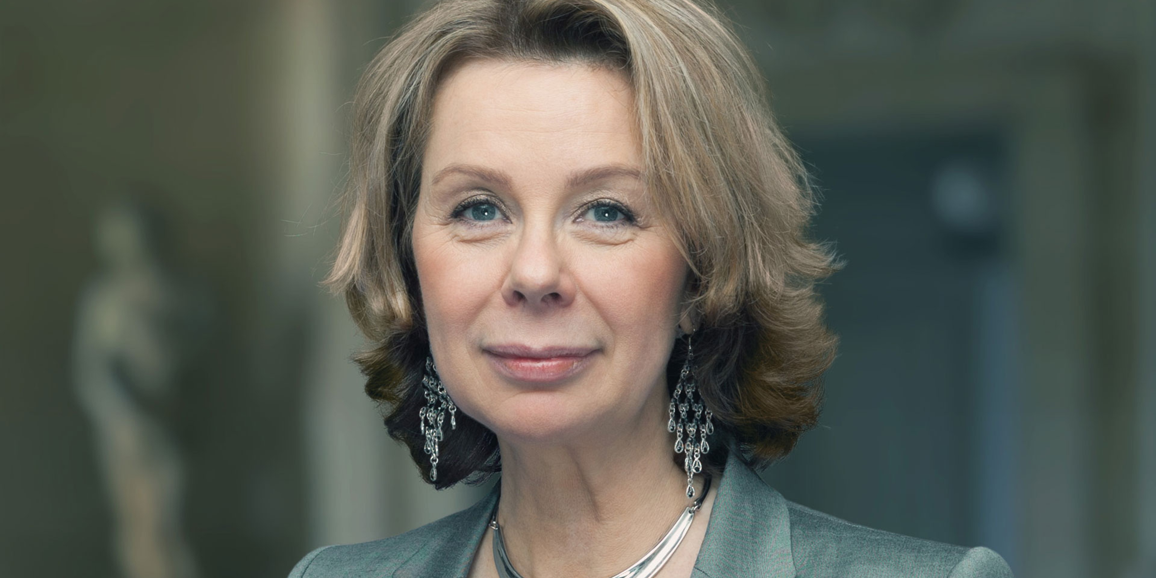 Ann-Sofi Söderqvist står framför en fond av noter och ler in i kameran