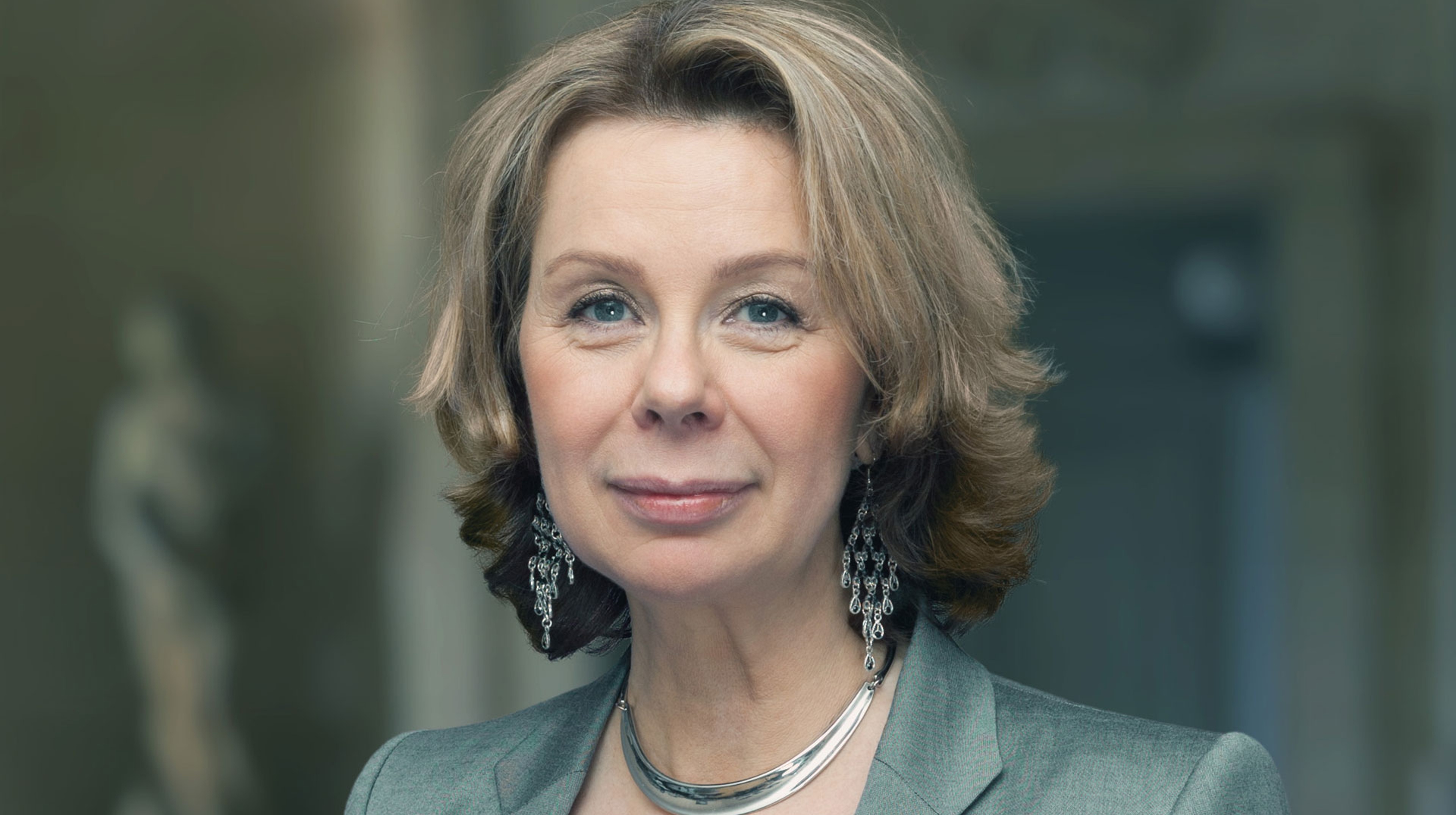 Ann-Sofi Söderqvist står framför en fond av noter och ler in i kameran