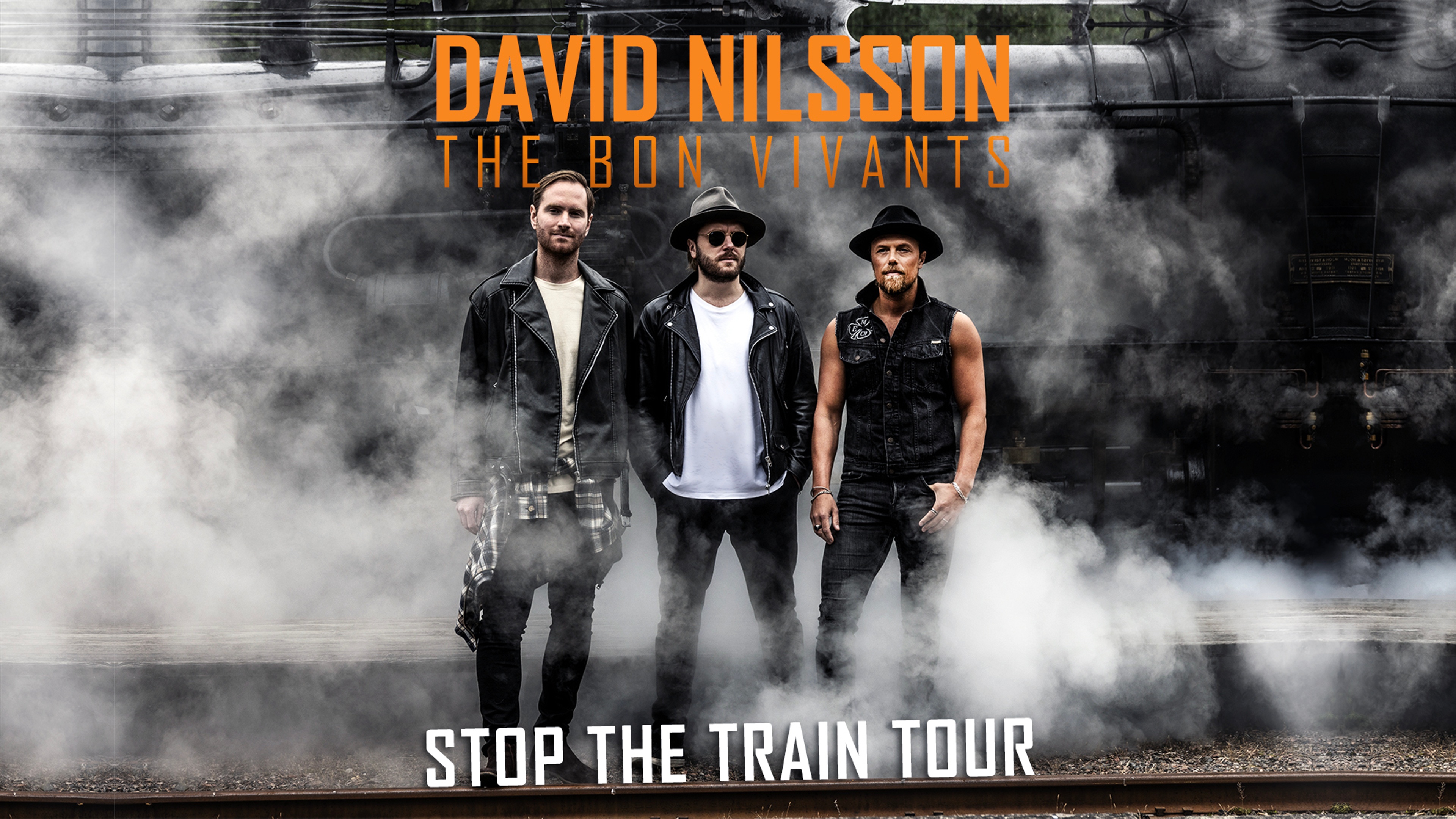 De tre medlemmarna står på rad vid ett ånglok med rök. Text: Stop the train tour