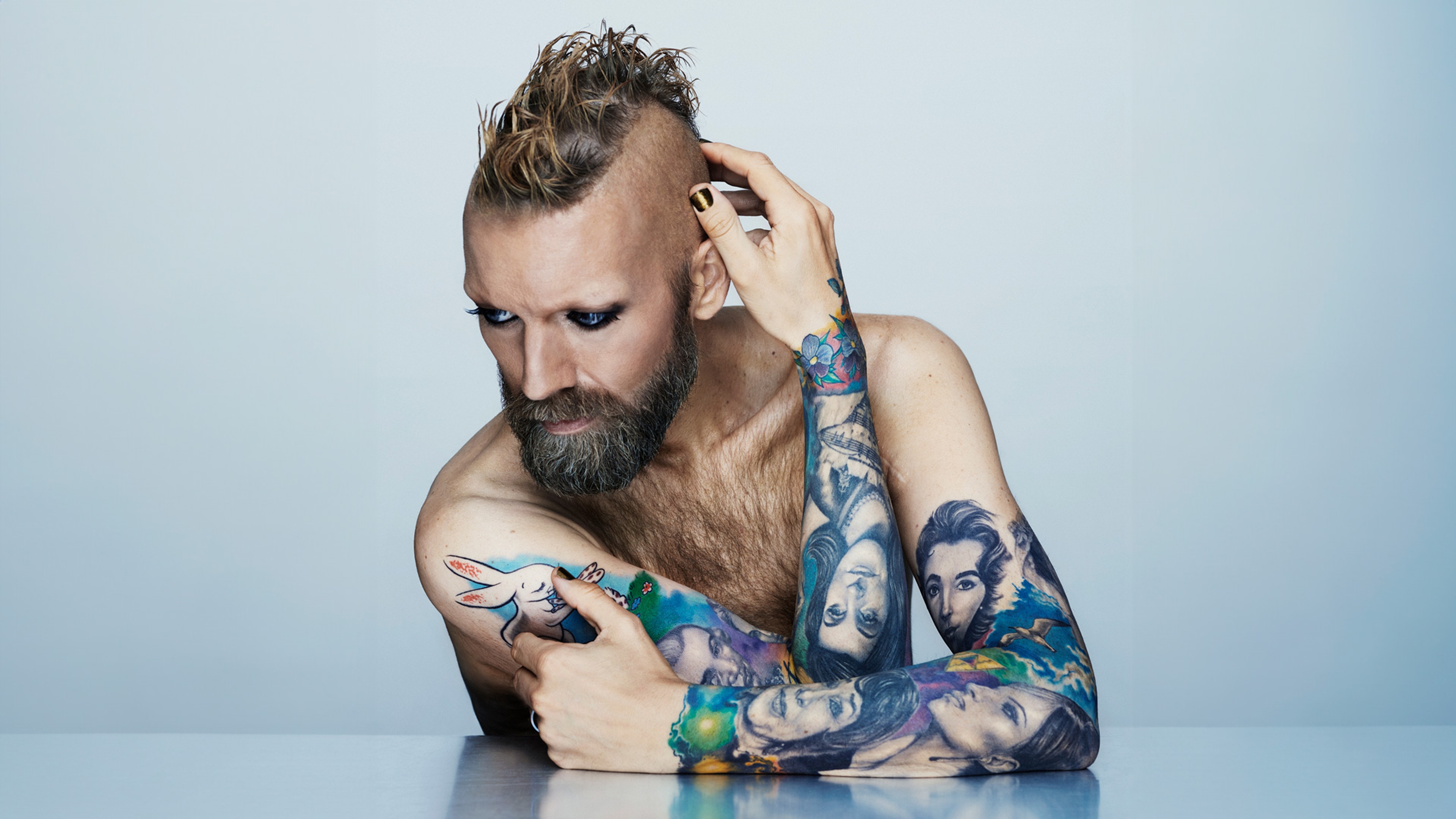 Rickard Söderberg sitter i bar överkropp vid ett bord och håller om sig själv och tittar snett neråt