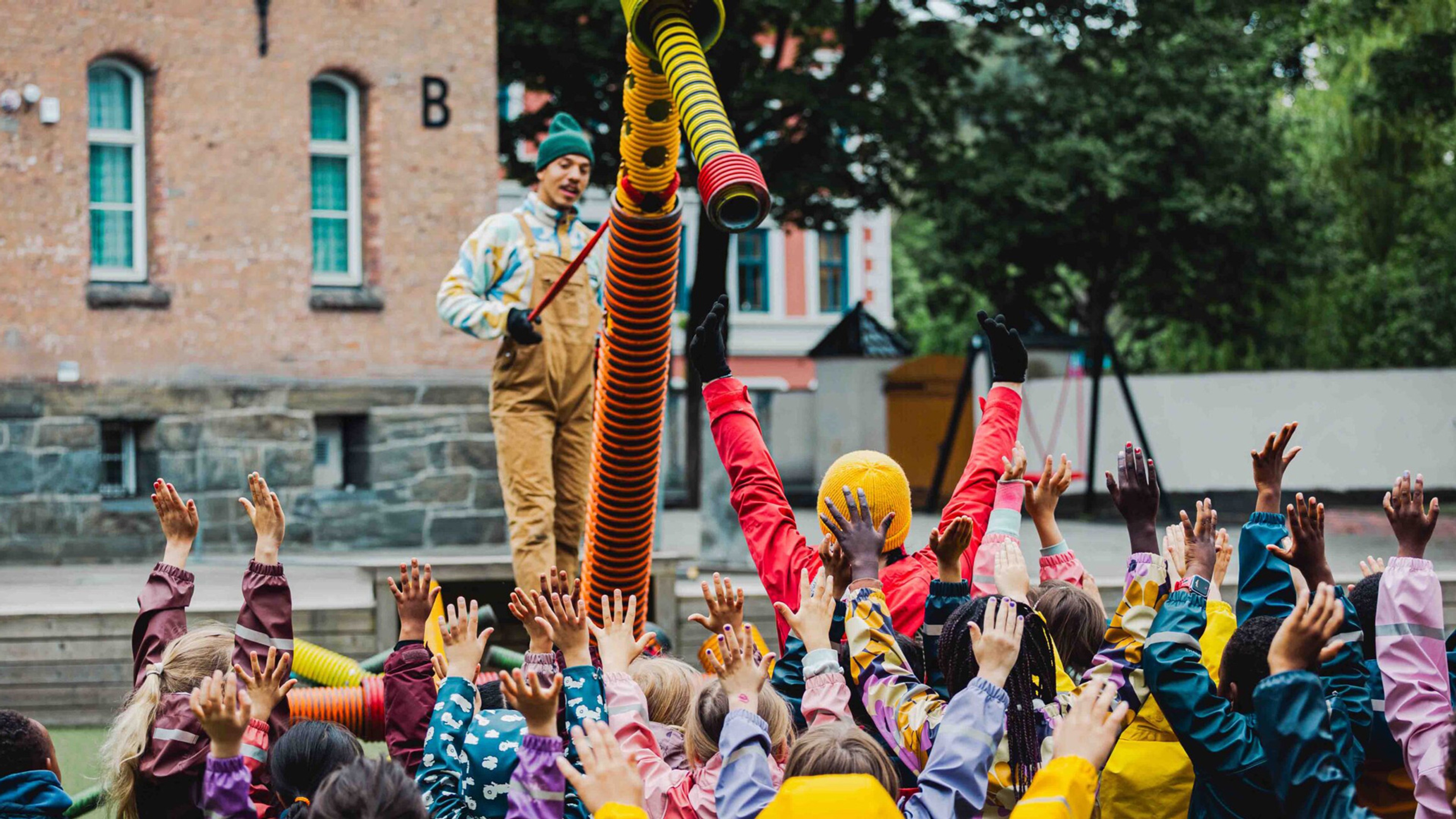 Barn men uppsträckta armar framför en pryl men ihopsatta rör. 