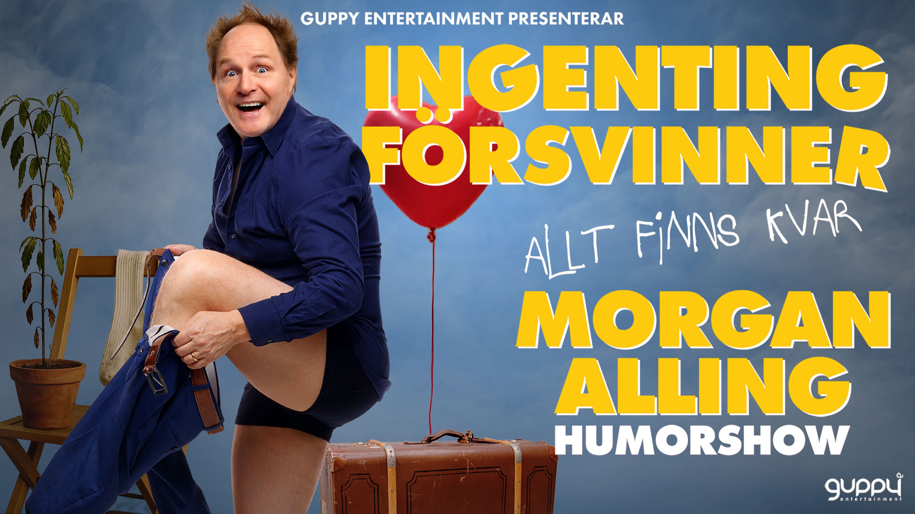 Morgan Alling tar på sig ett par byxor i ett rum med blommor, ballonger och en väska.