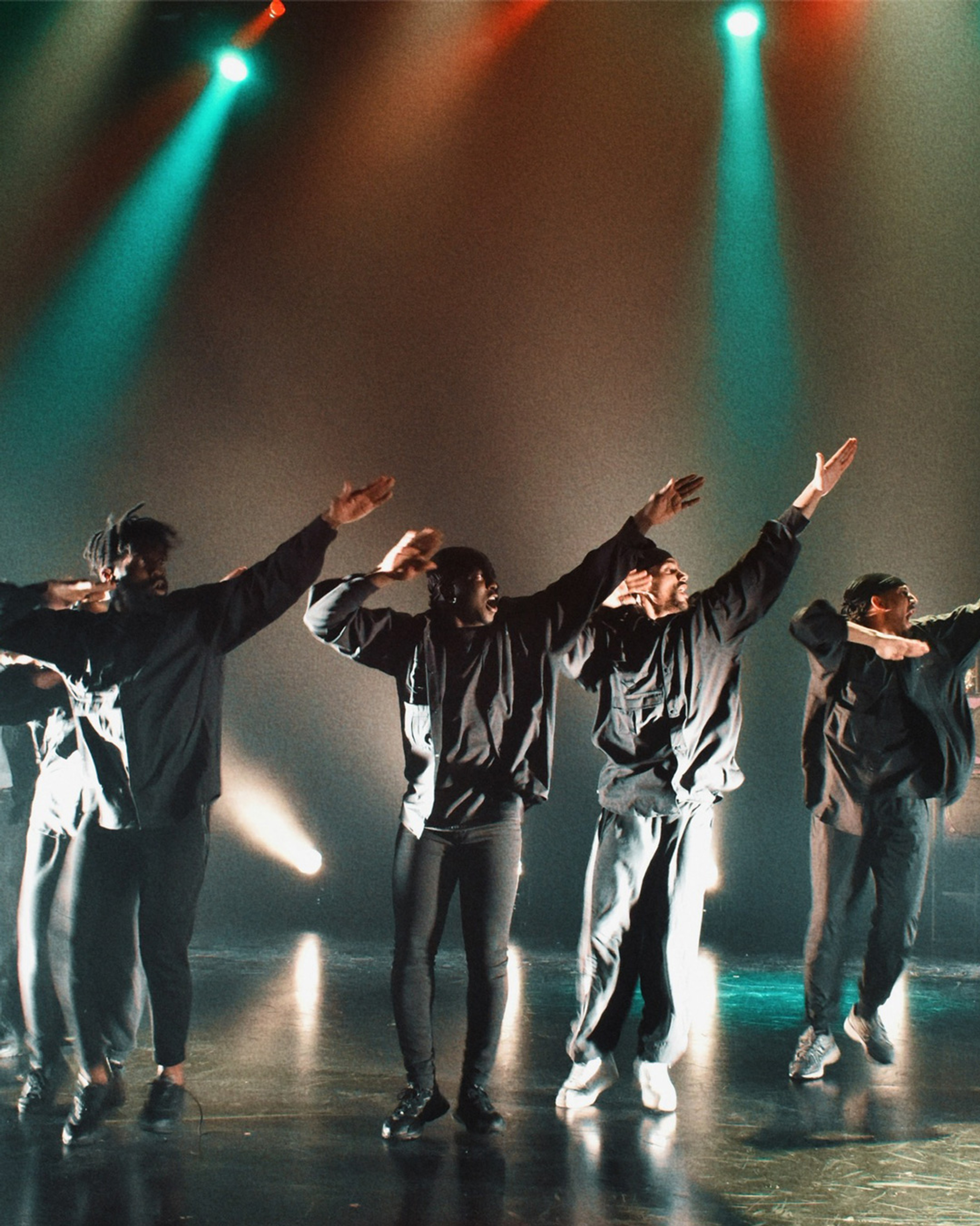 Fem dansare i rörelse på scen.