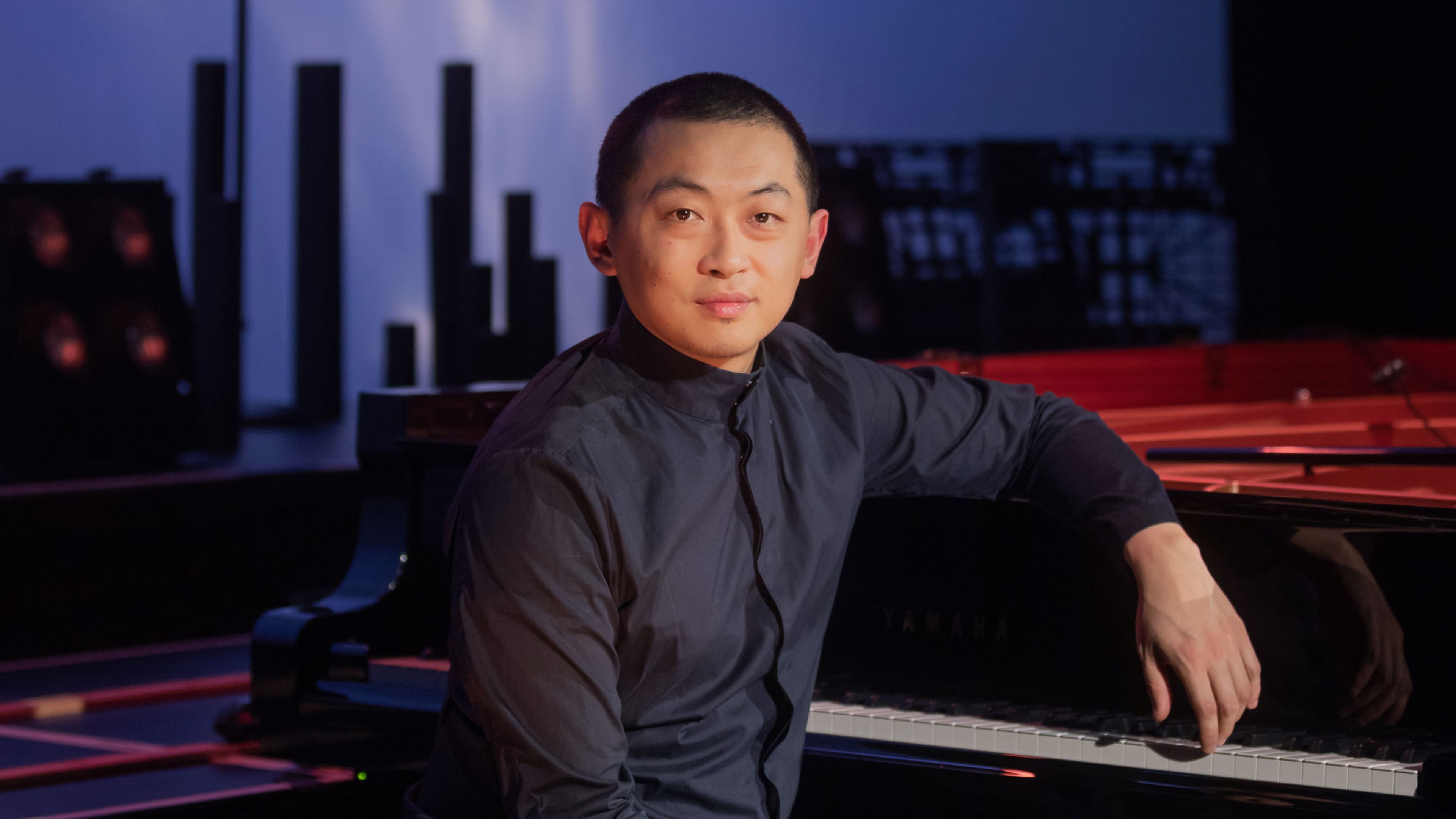 Porträttbild på David Huang vid ett piano.