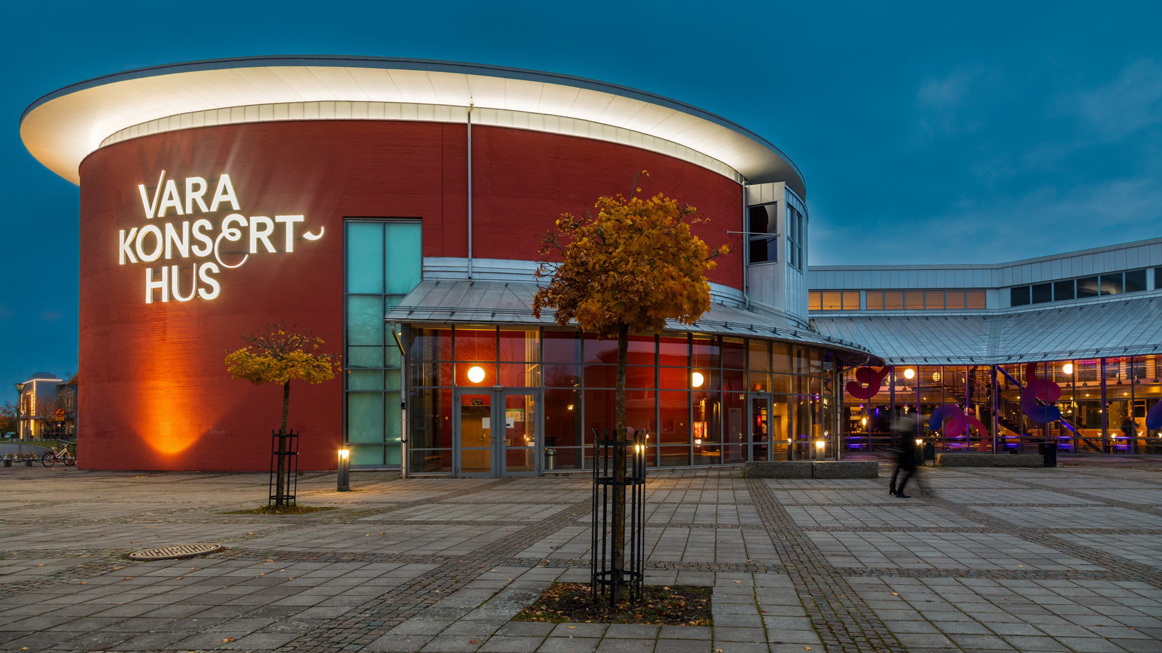 Vara Concert Hall in the evening light during autumn with people on their way into the house