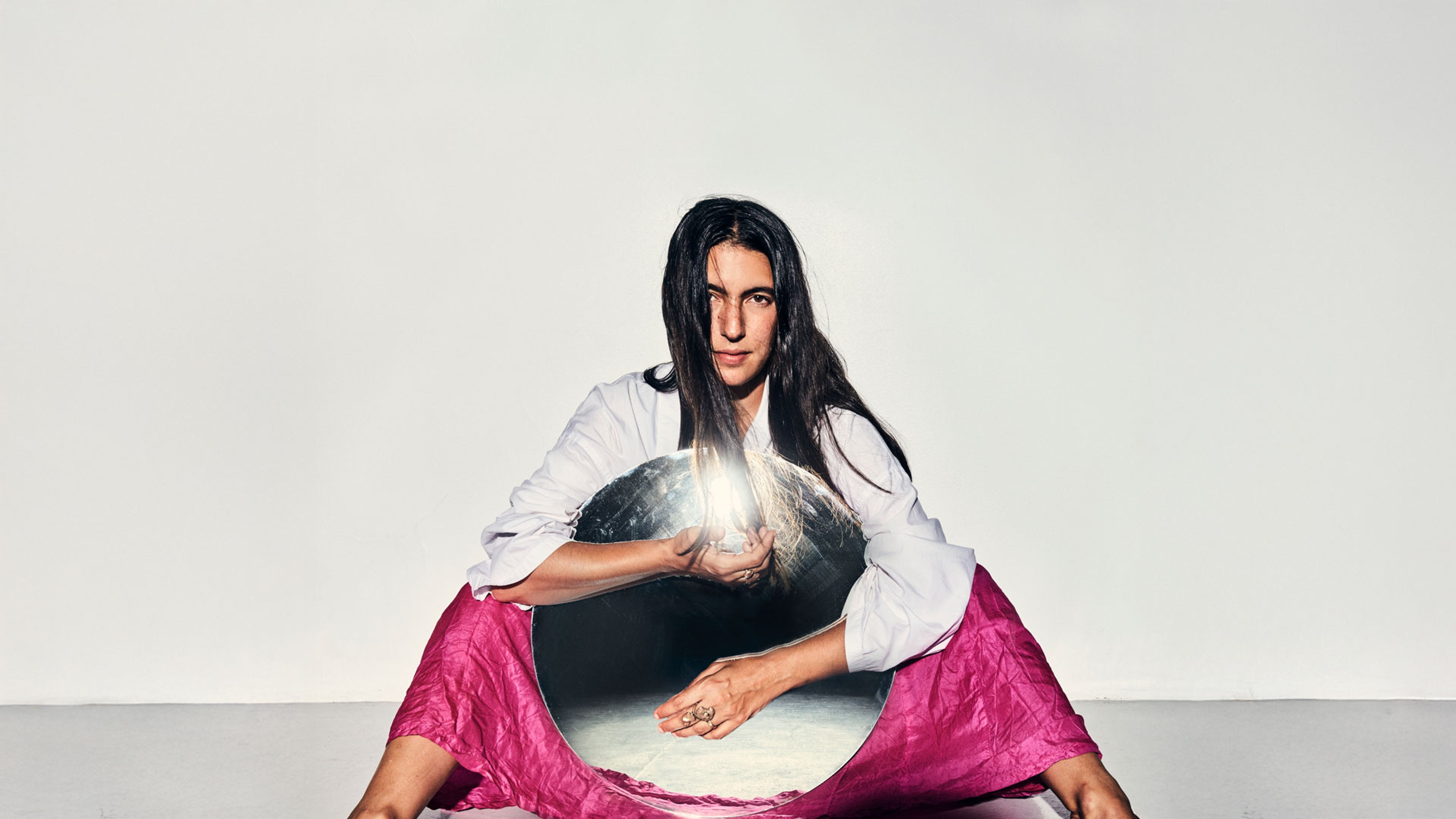 Mariam sitter på golvet mot vit bakgrund.