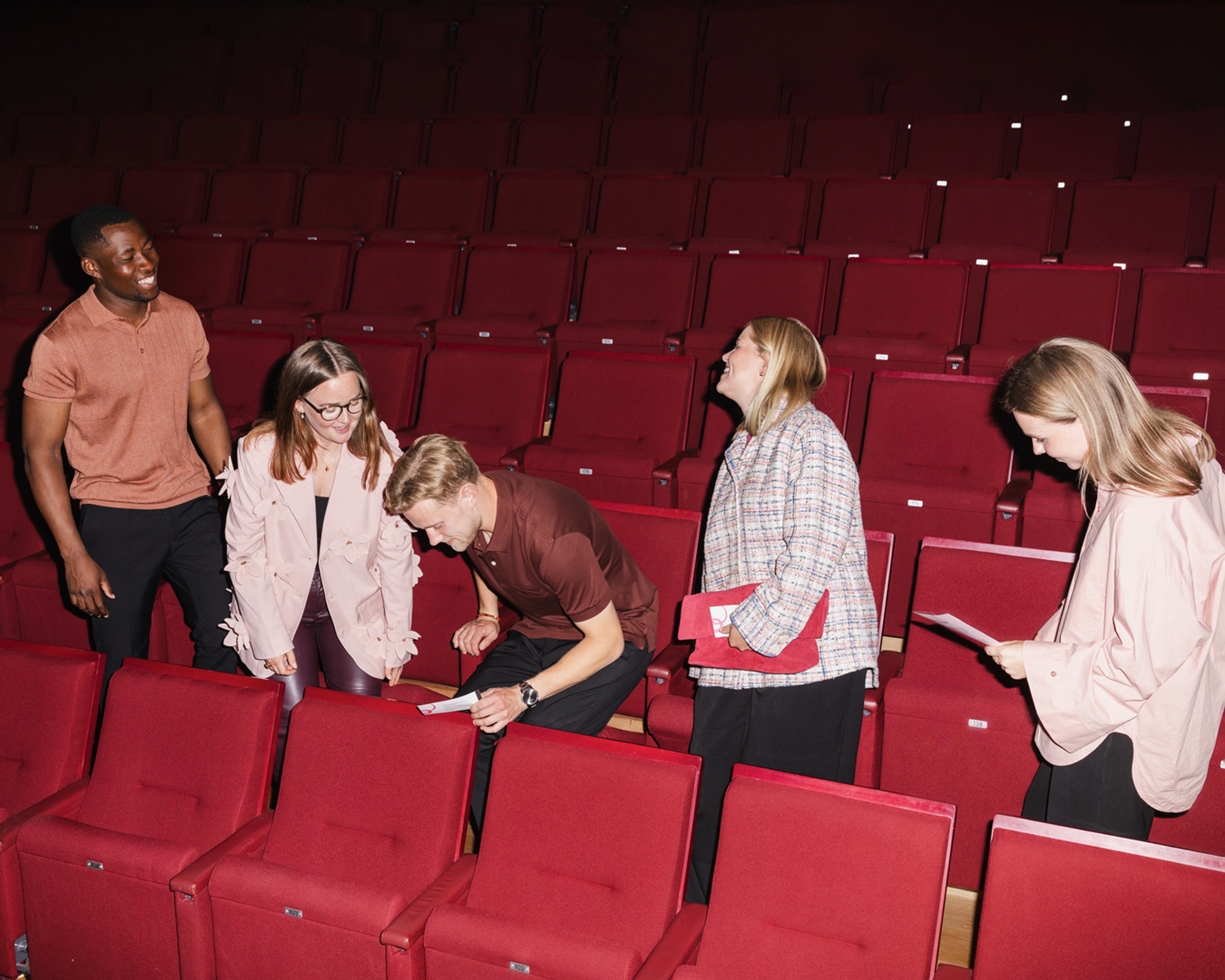 Fem unga personer sätter sig i konsertsalen.