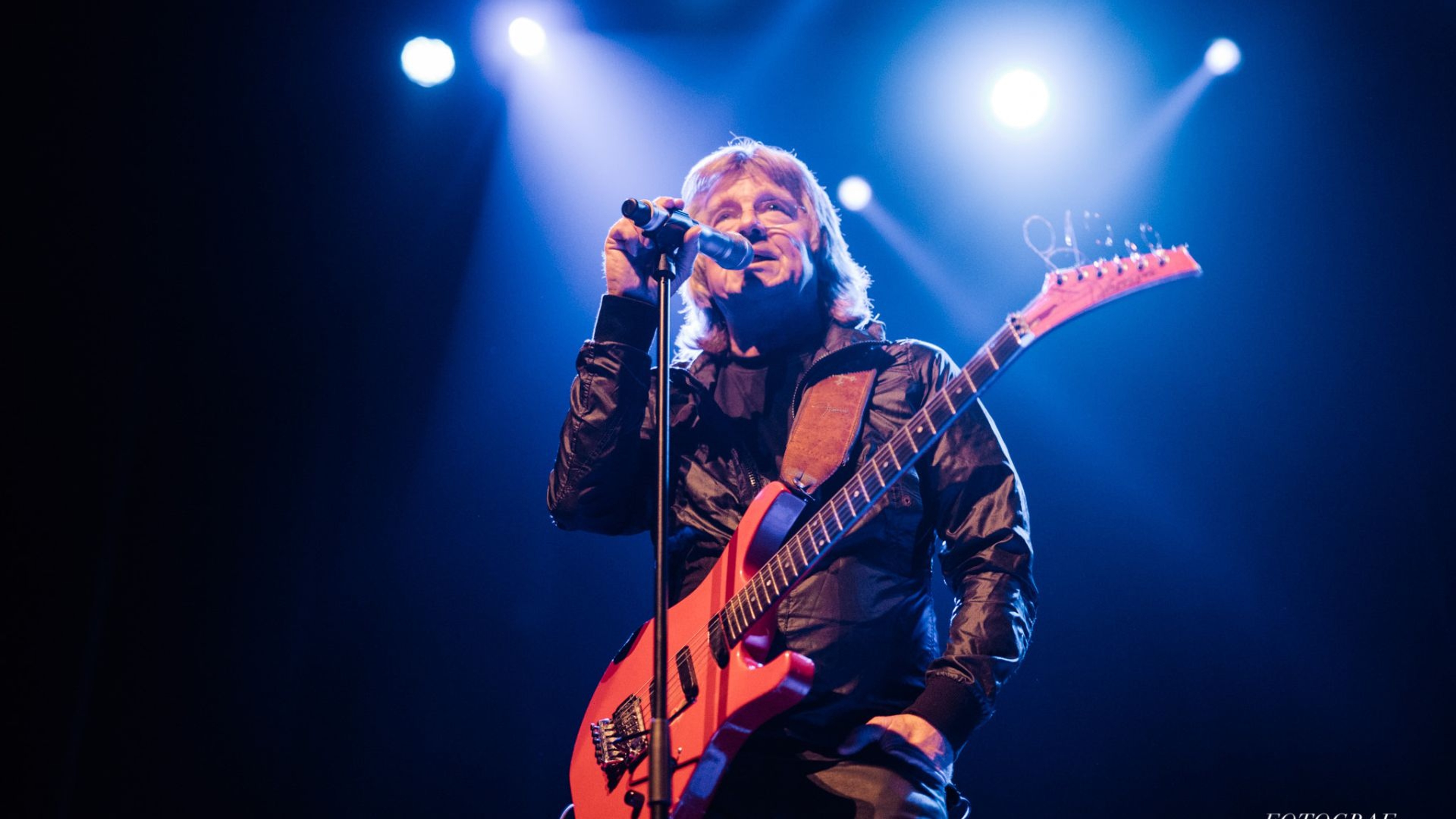 Janne Schaffer står på scen med en mikrofon och gitarr