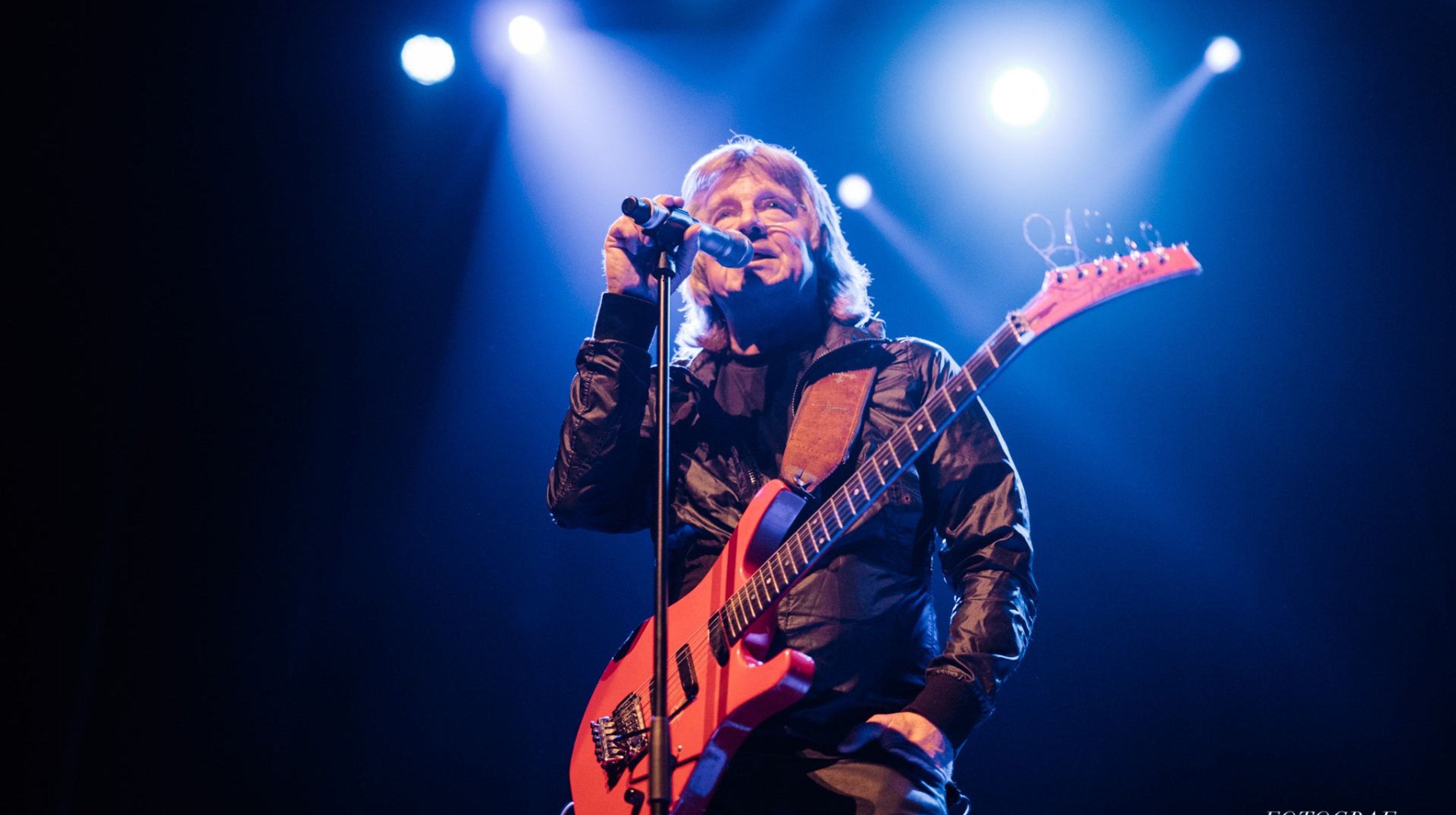 Janne Schaffer står på scen med en mikrofon och gitarr 