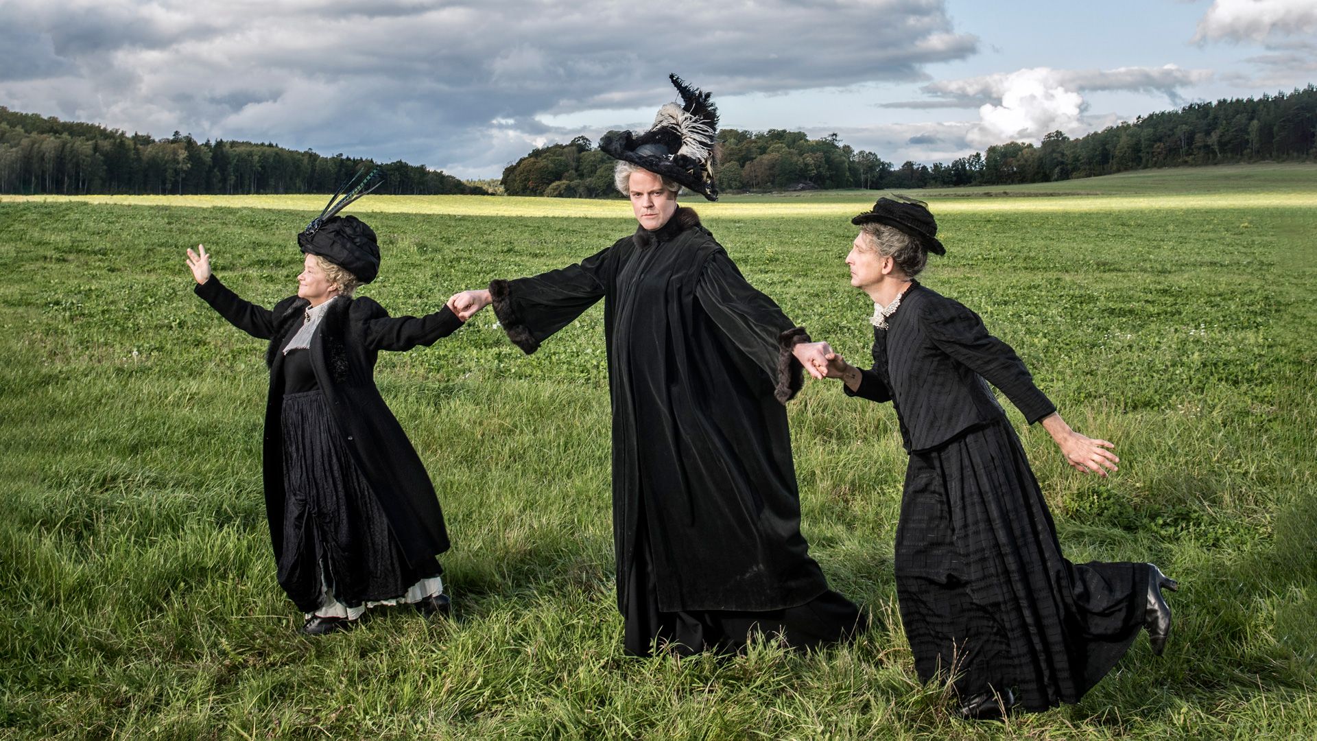 Ensemblen ur Uppdrag Holgersson utklädda till Selma Lagerlöf på en äng.