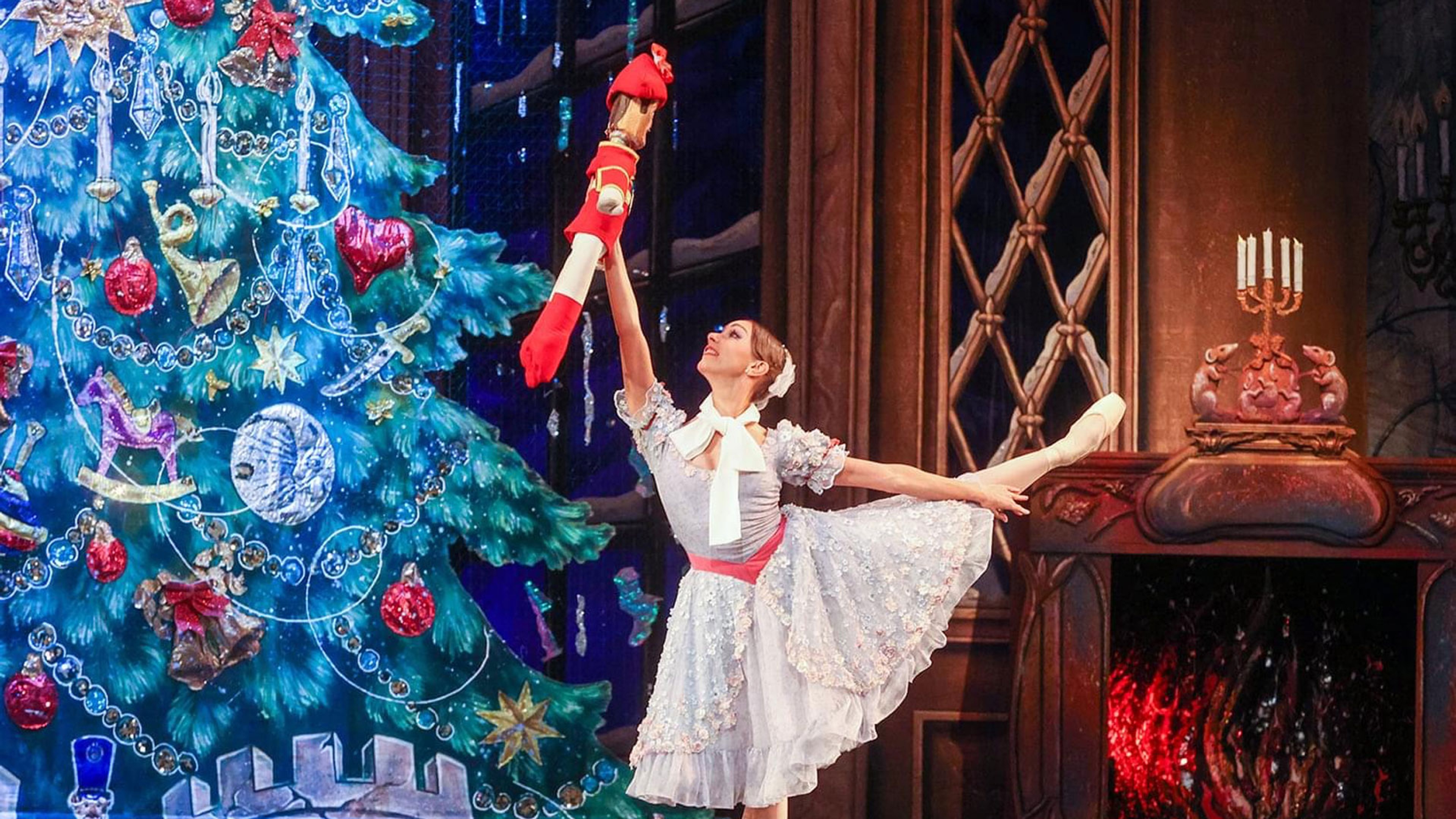 En balettdansös dansar framför en julgran och en öppen brasa
