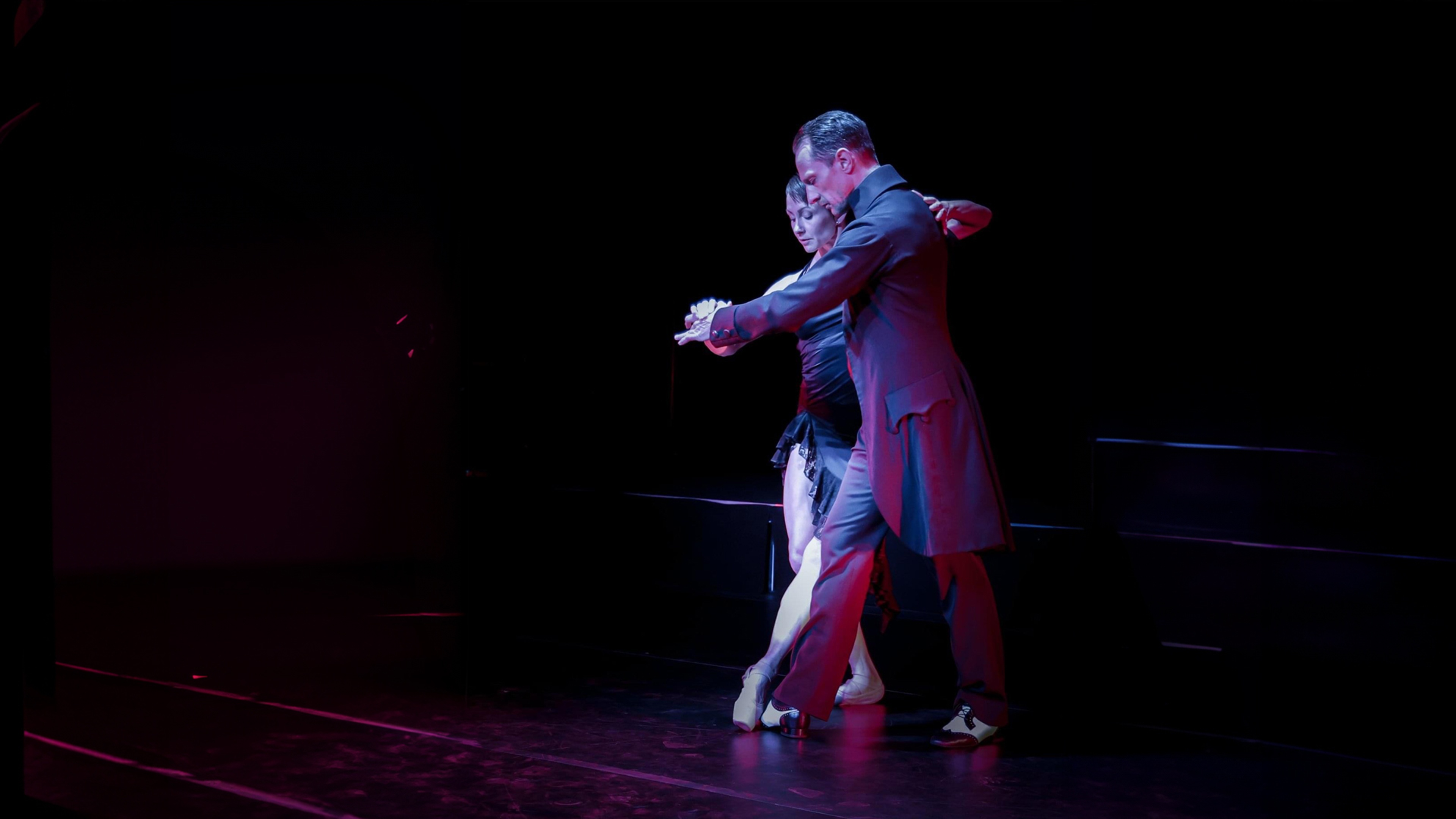 Kvinna i ballerinaskor dansar pardans med en man i frack.