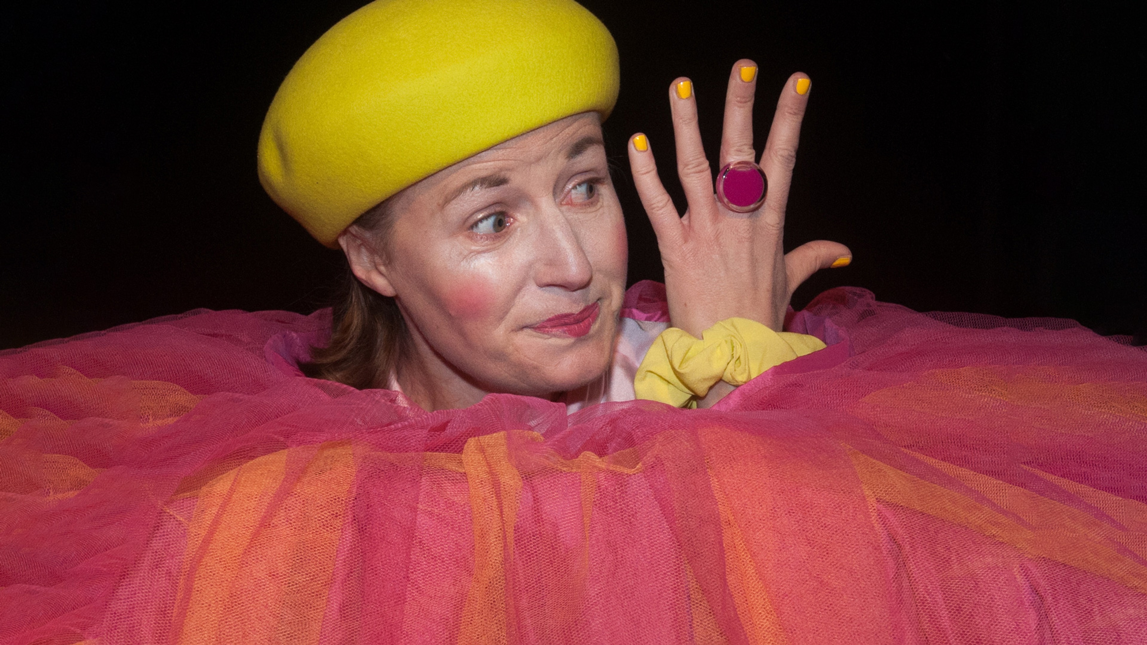 En kvinna i färglada kläder kikar fram ut en stor kjol.