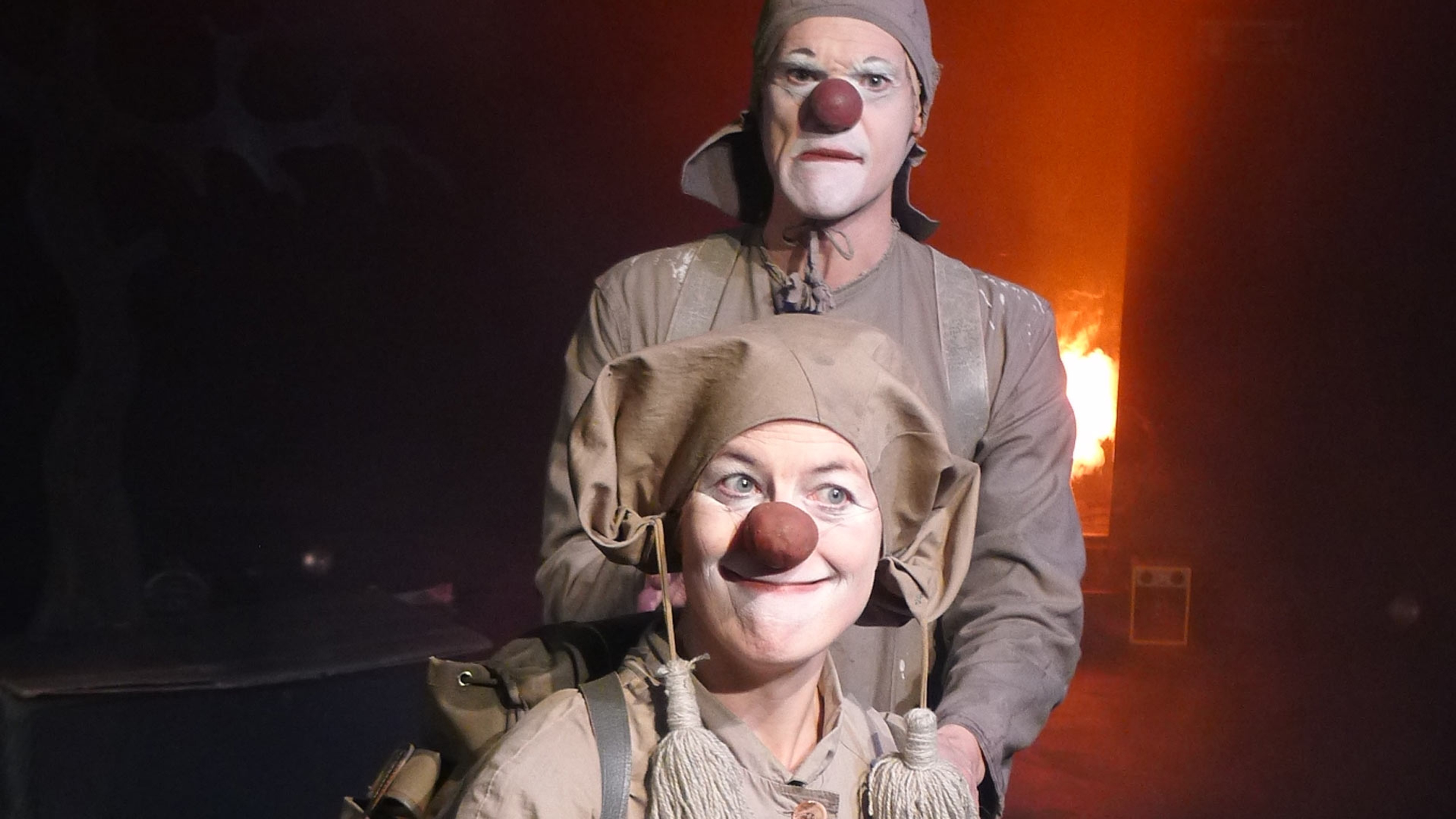 Två clowner klädda i gråa och beige kläder.