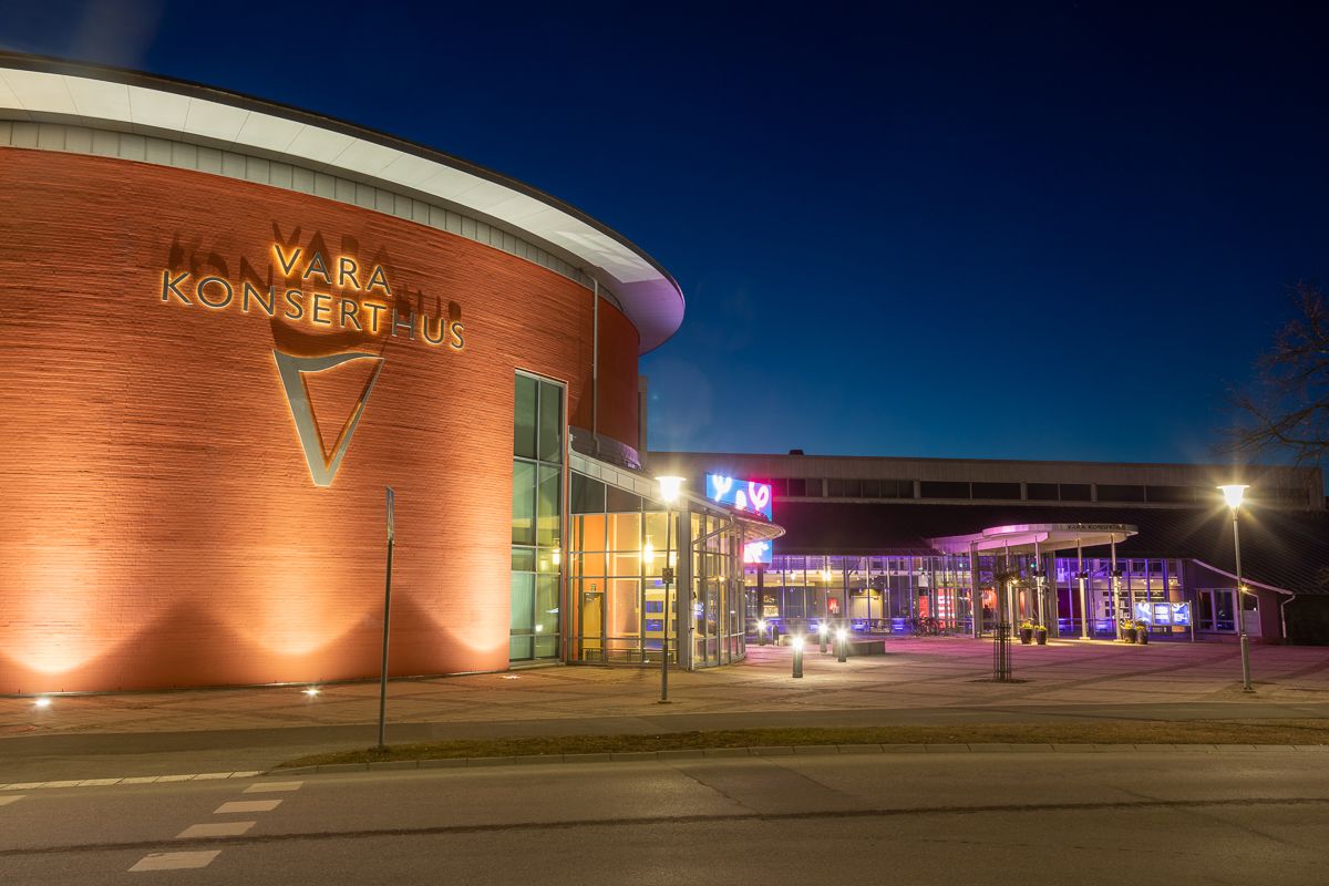 Vara Konserthus i mörker med tända spotlights som lyser upp och aktivitet inne i huset inför en konsert