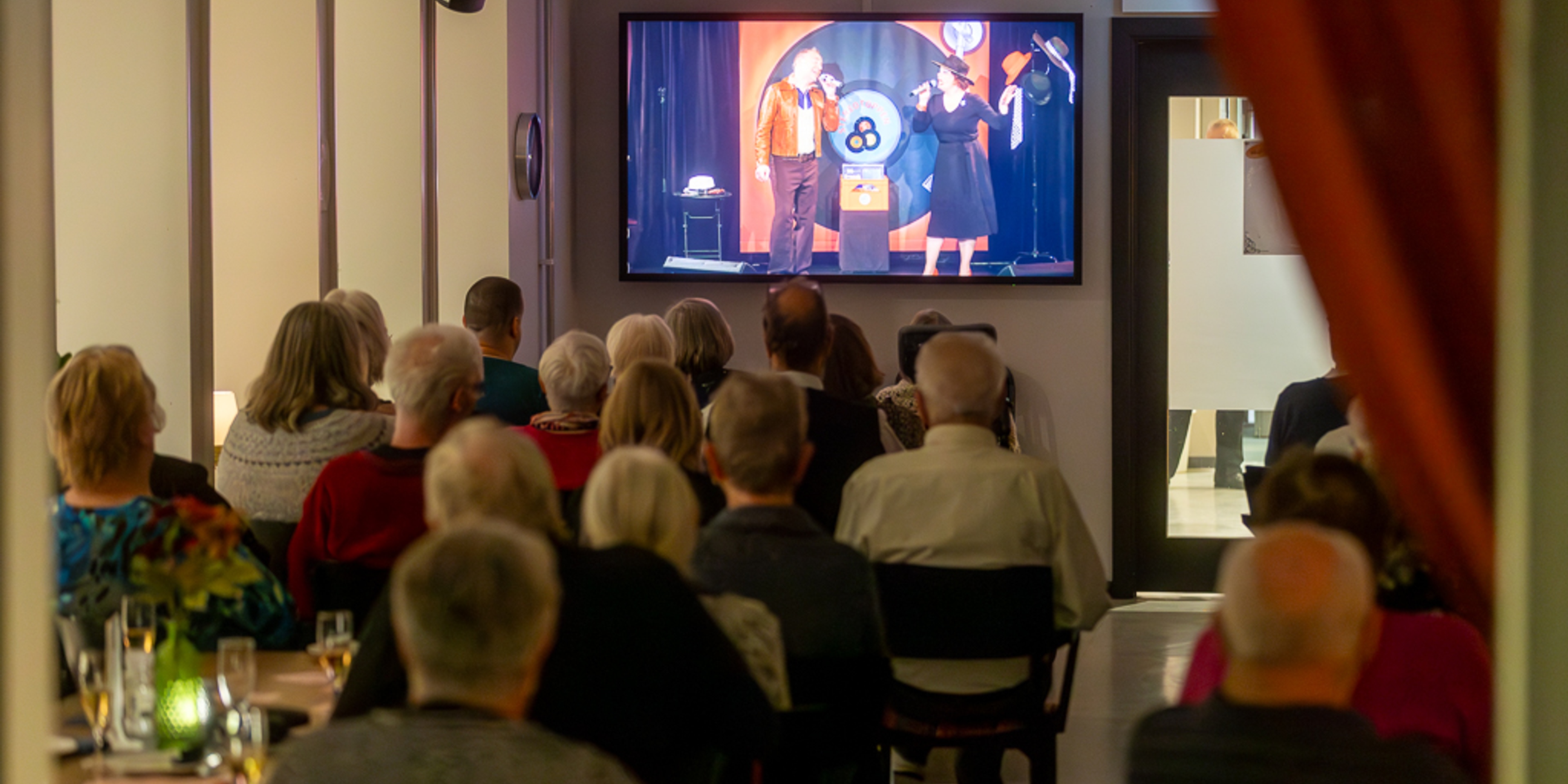 Publik sitter och tittar på digital scenkonst på ett av boende