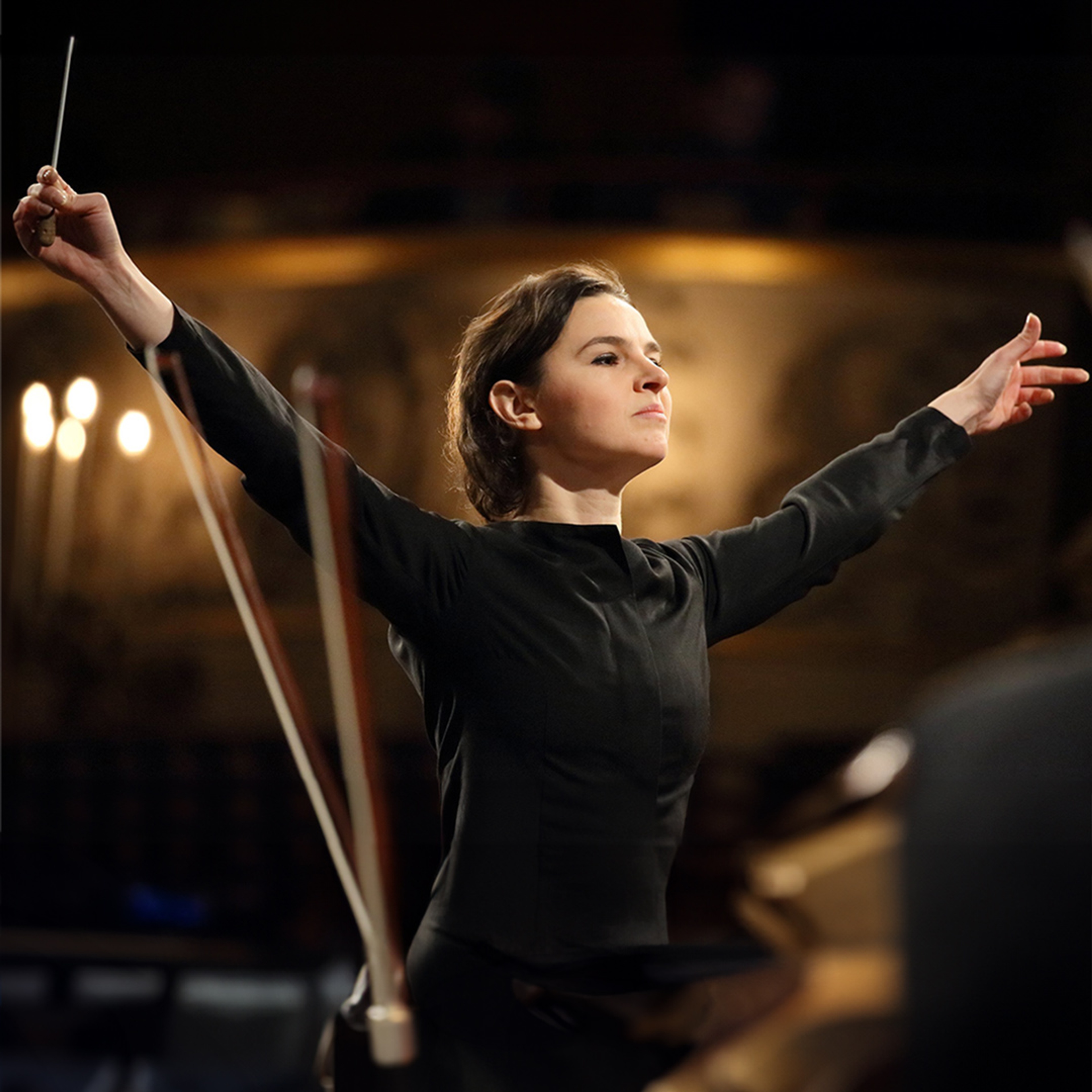 Kvinnlig dirigent med utsträckta armar.