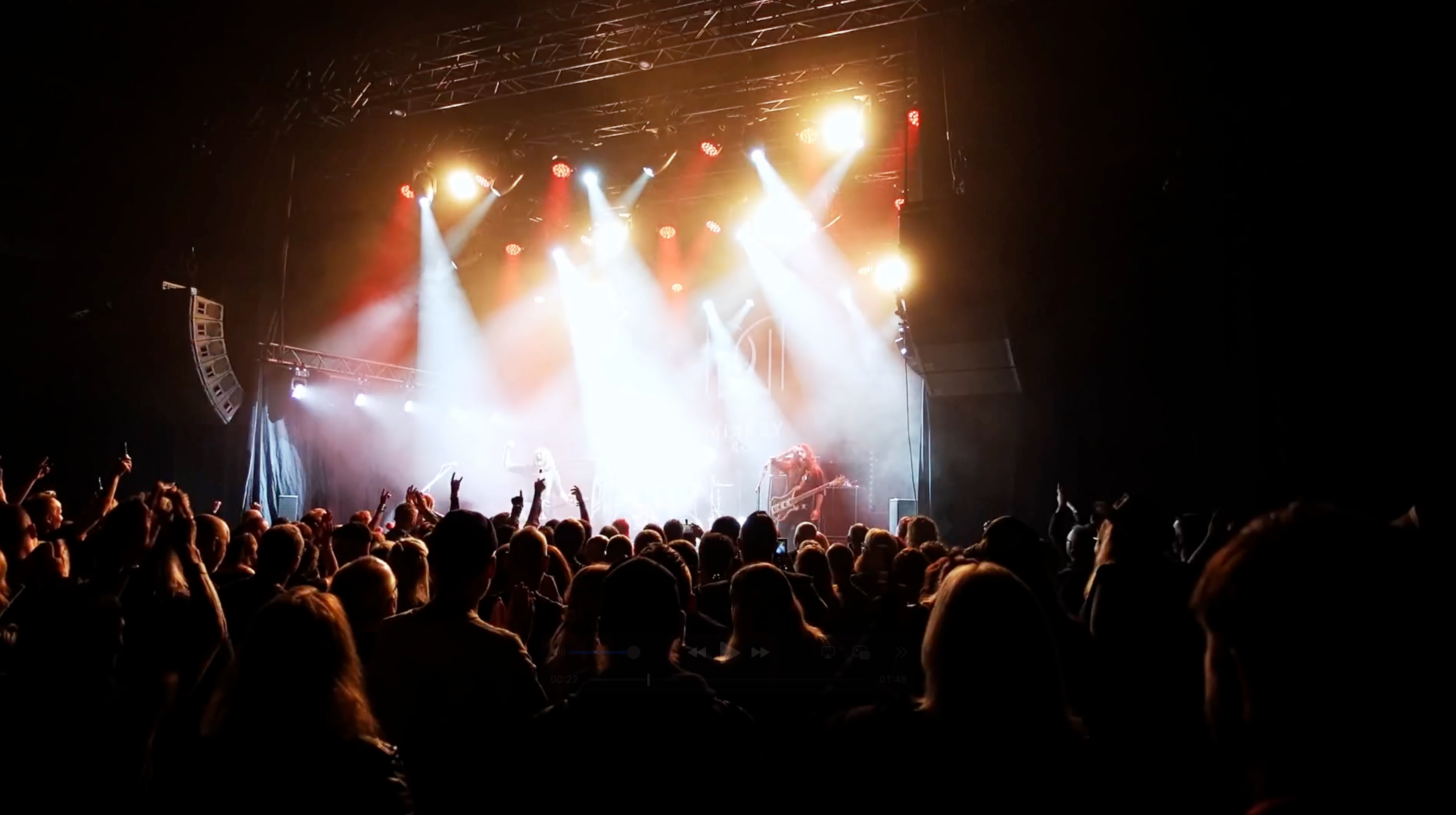 Rockkonsert med stående publik och mycket scenljus.