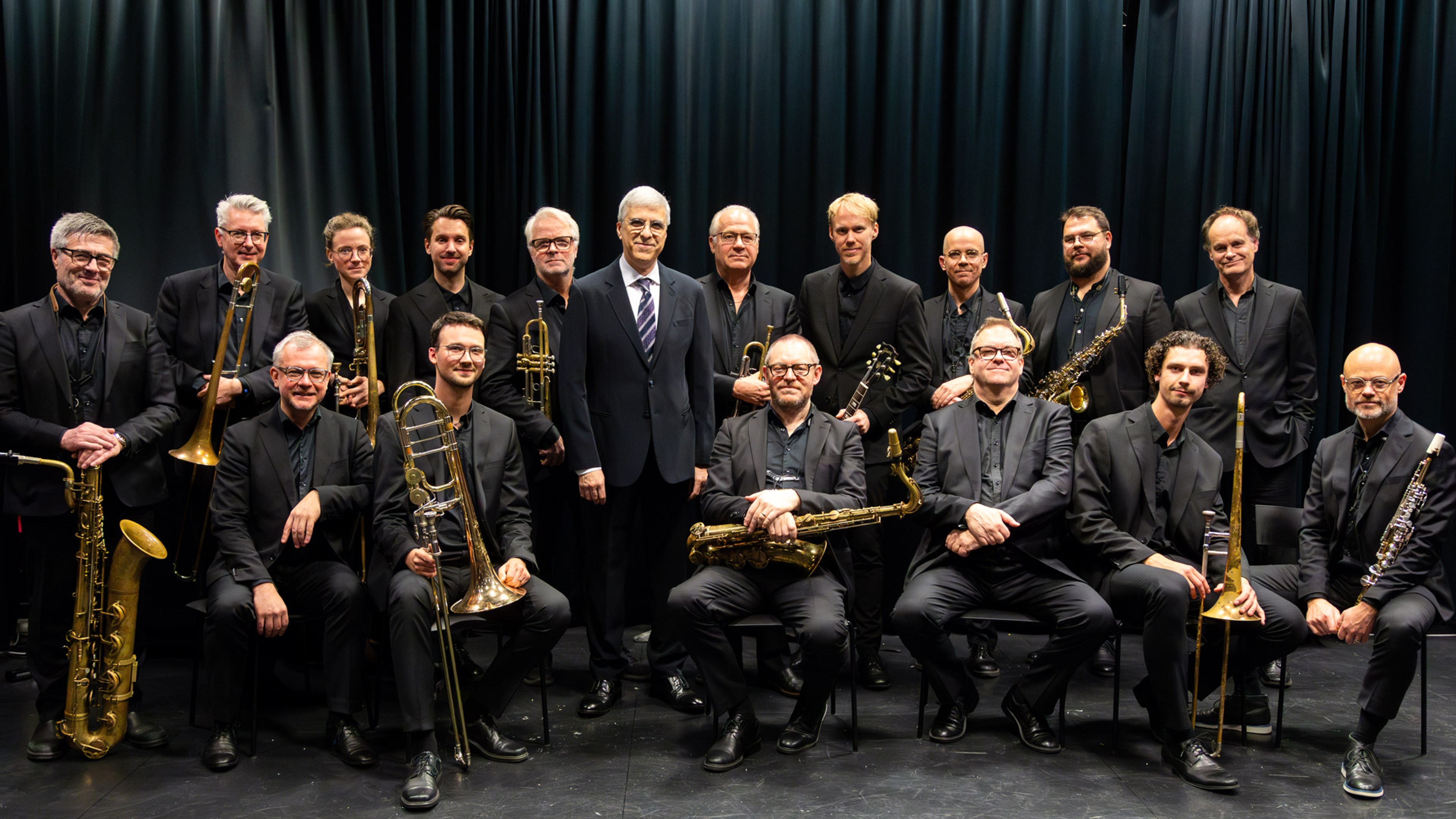 Bohuslän Big Band står med Vince Mendoza i mitten framför ett svart skynke