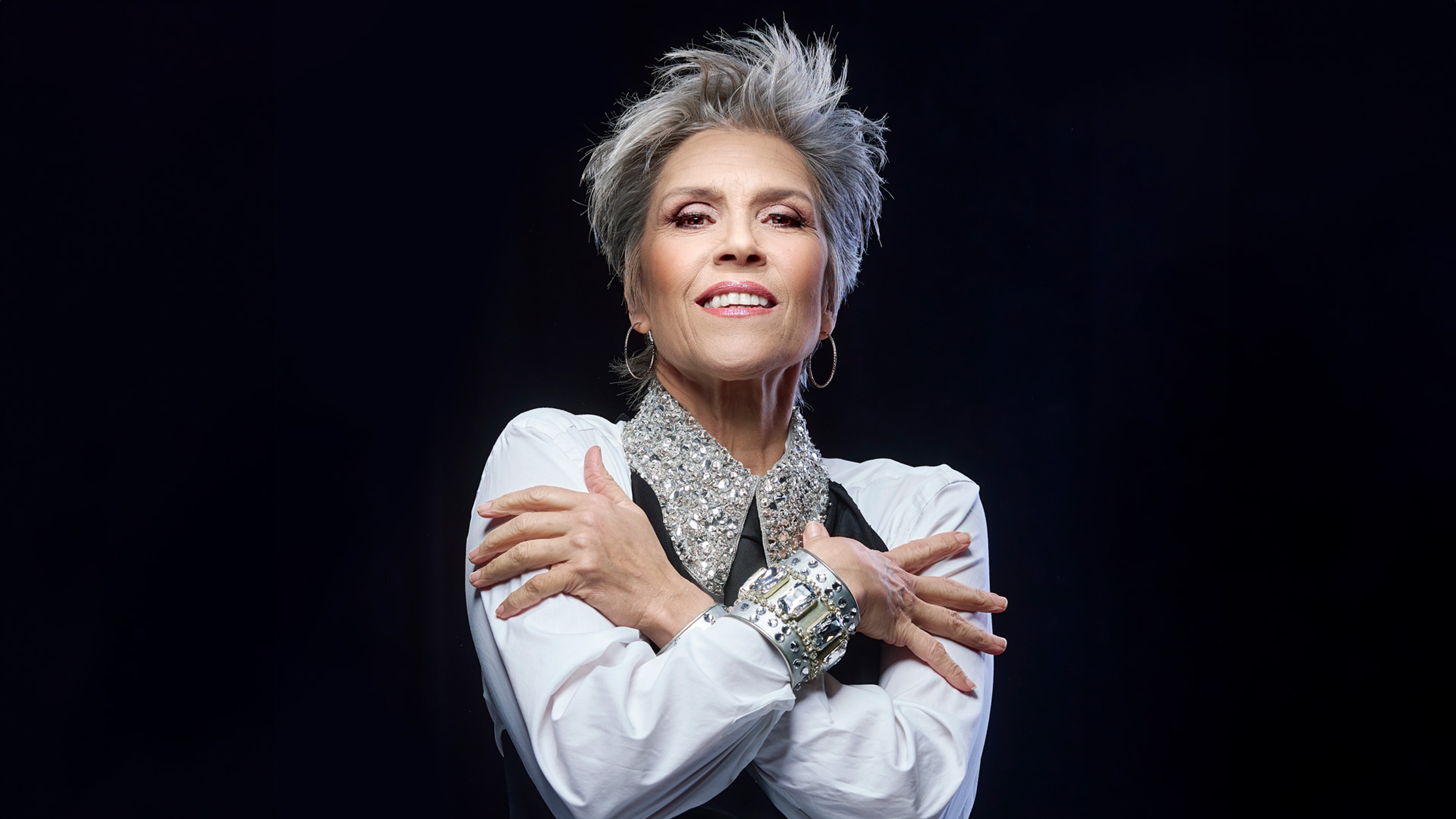 Petra uppklädd i glittriga smycken i en pose med armarna över bröstet.