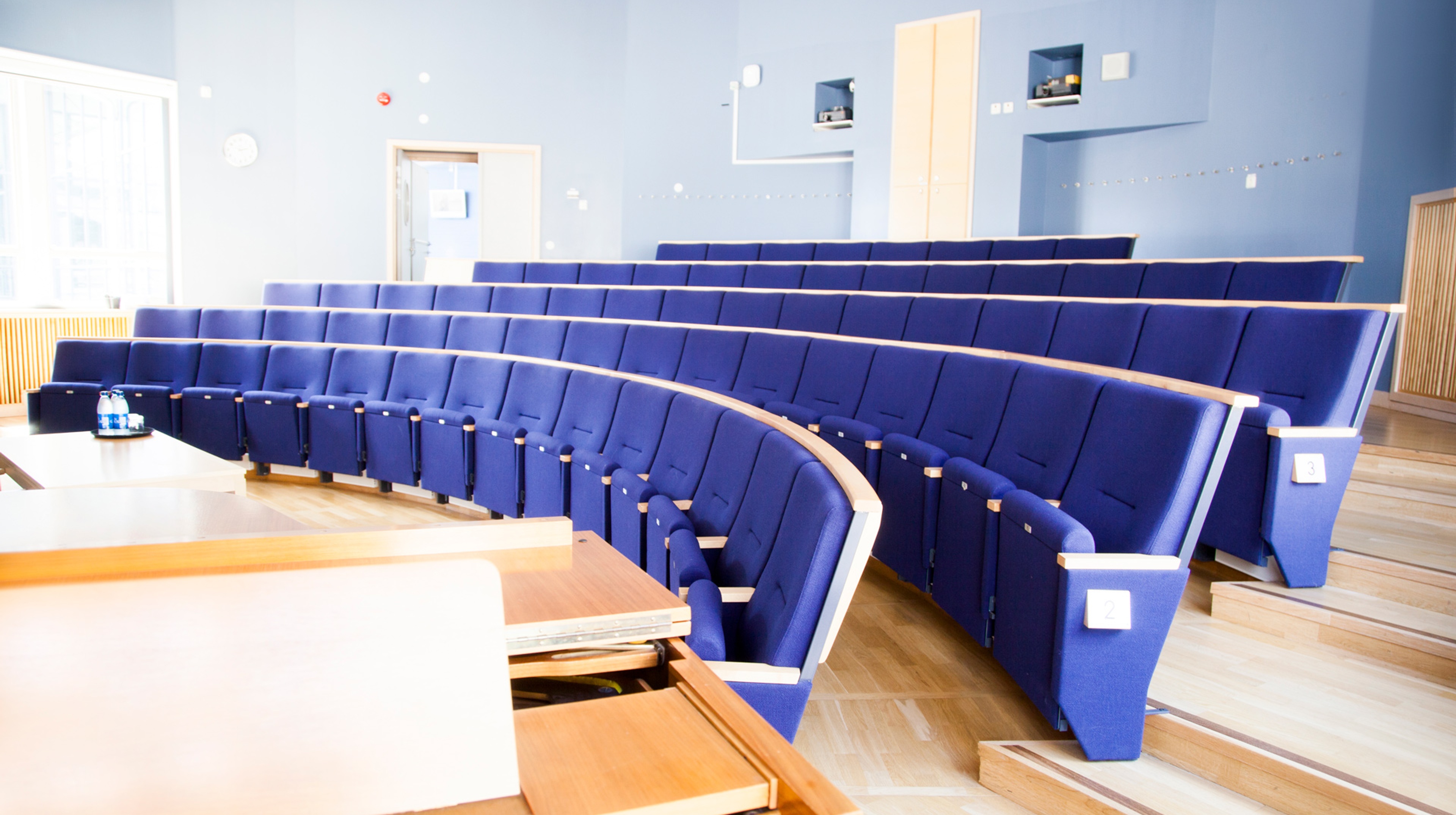 Konferenssal med många mjuka sittplatser. Stolar med utfällbar sits i gradänger.