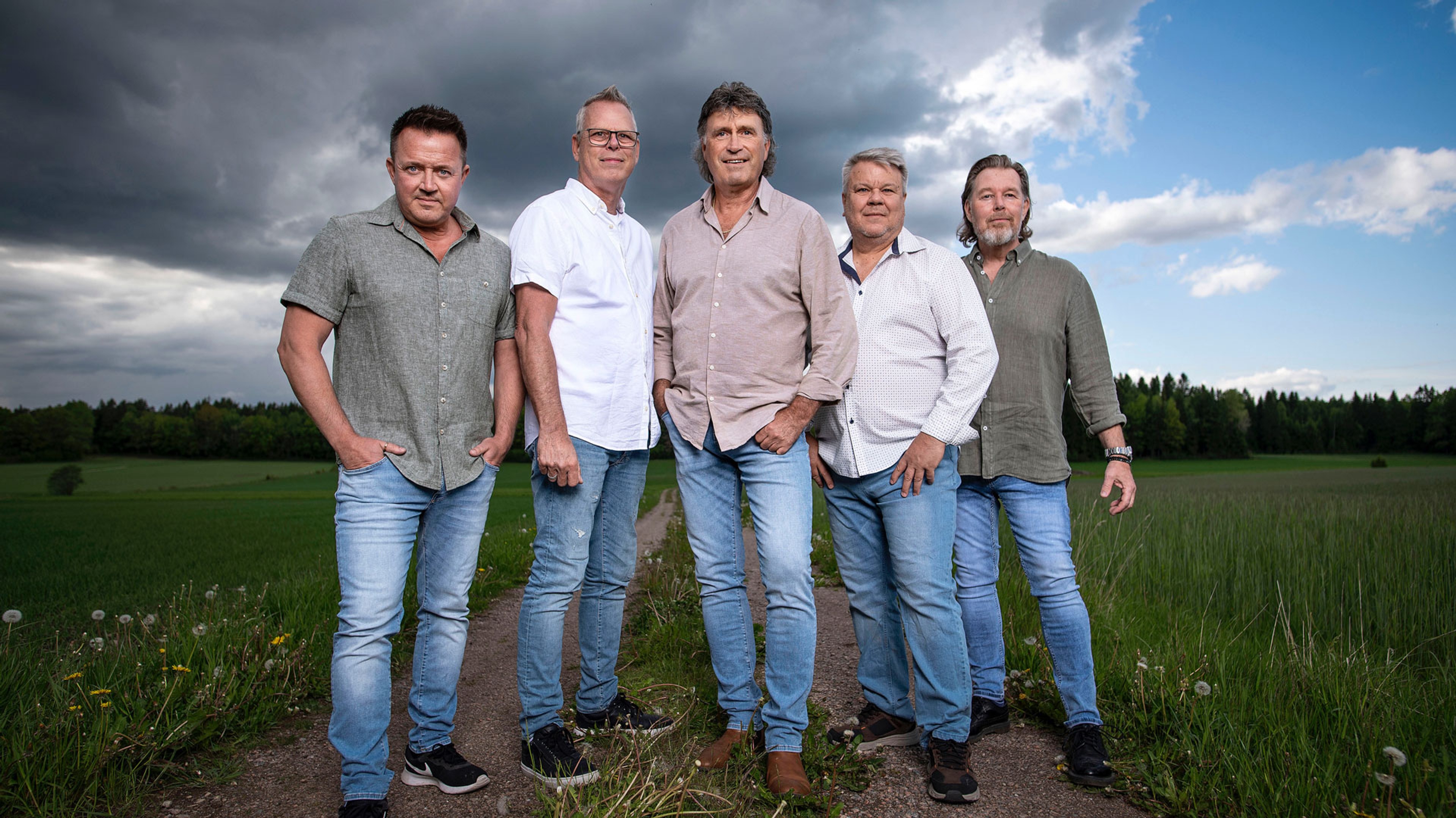 Medlemmarna i Streaplers står bredvid varandra utomhus intill gröna åkrar.