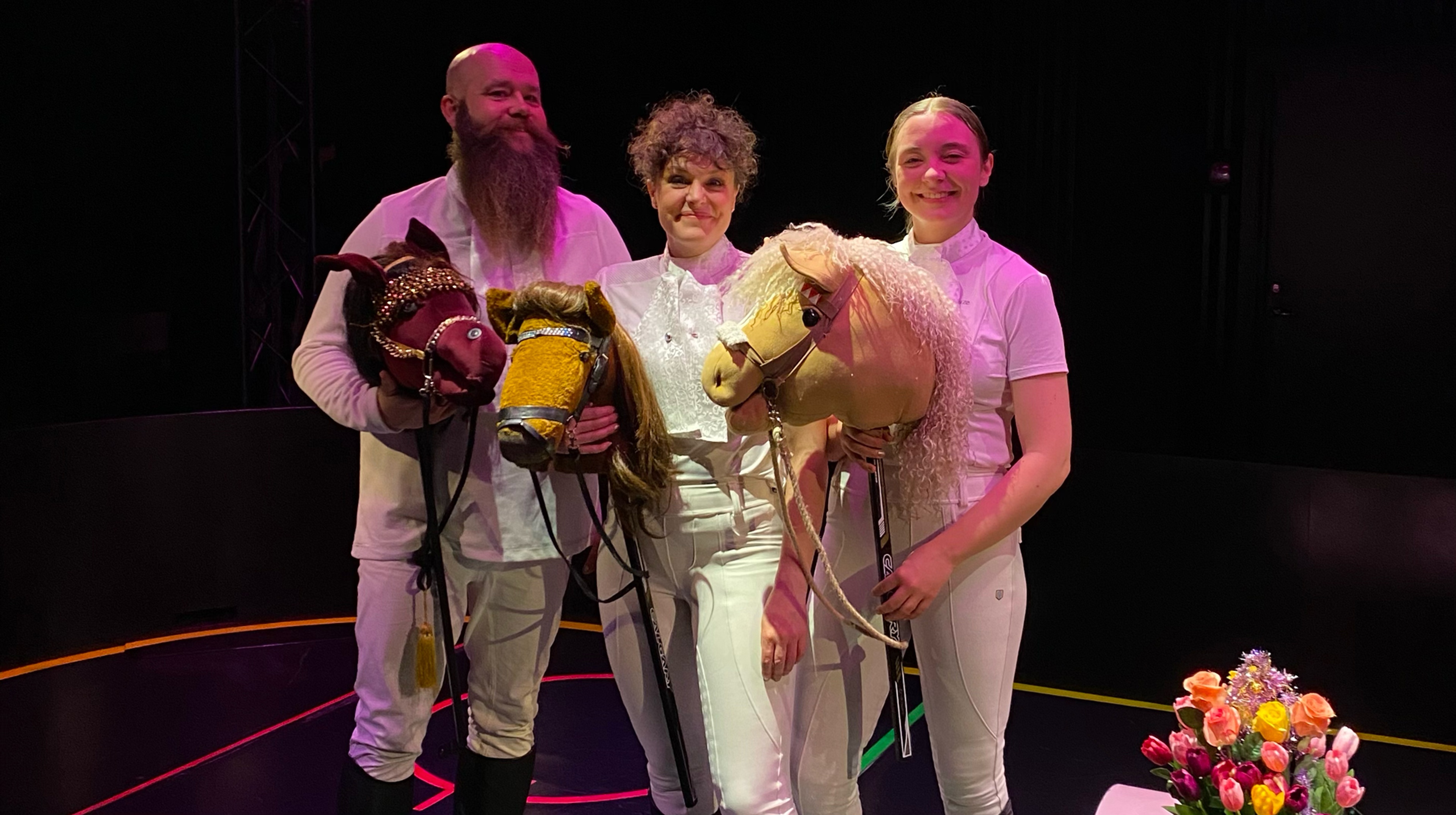 Tre personer med käpphästar i en hockeyrink.