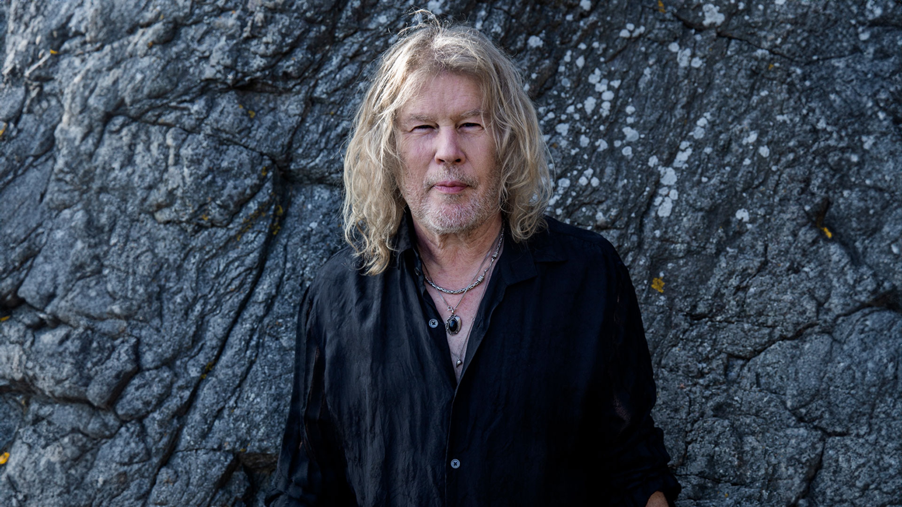 Staffan Hellstrand iklädd svart skorta framför en bergvägg.