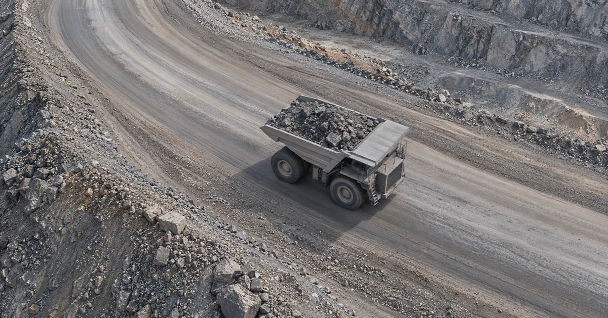 An overhead view shows a loaded haul truck following a curving mine road.