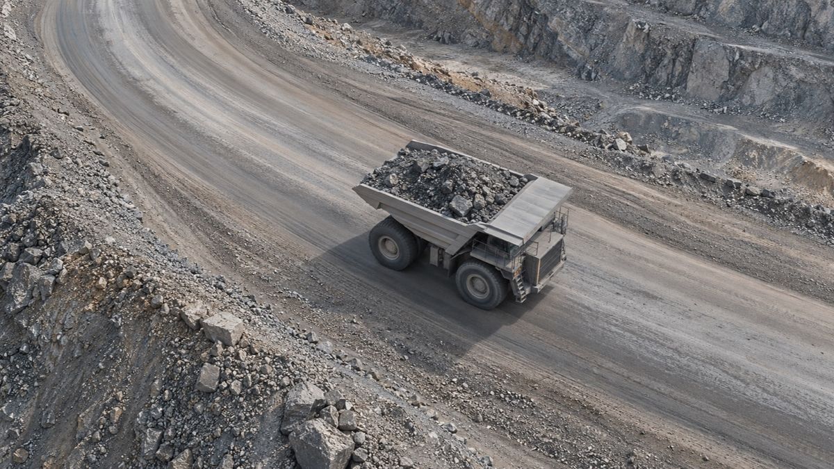 An overhead view shows a loaded haul truck following a curving mine road.