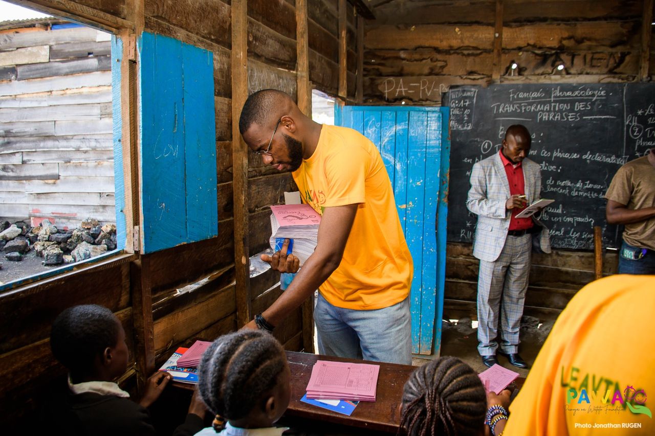 Distribution de cahiers sur les pupitres d'une classe de Goma, en RDC