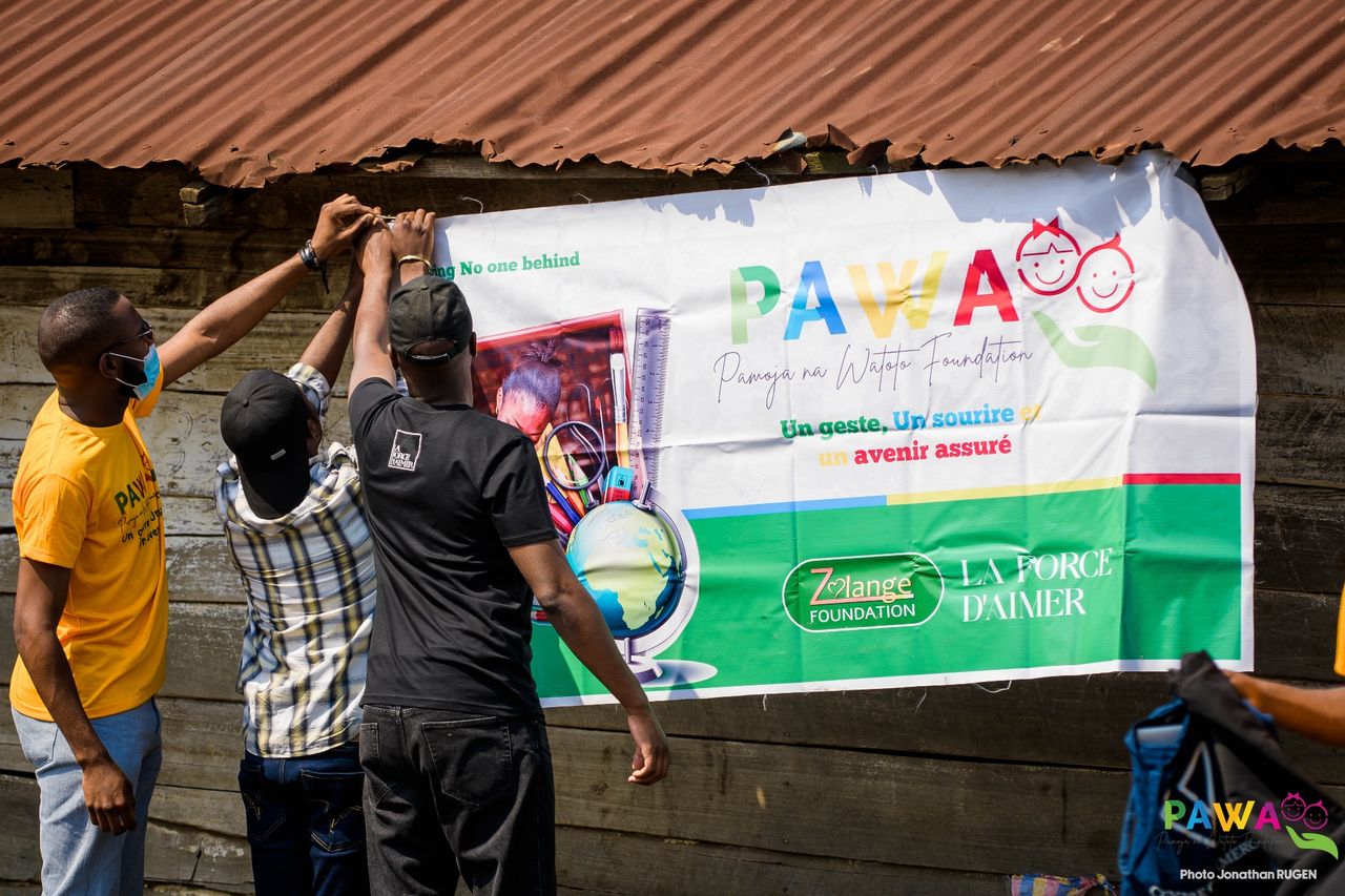 Installation de la bannière PAWA Foundation et La Force d'Aimer avant une distribution à Goma