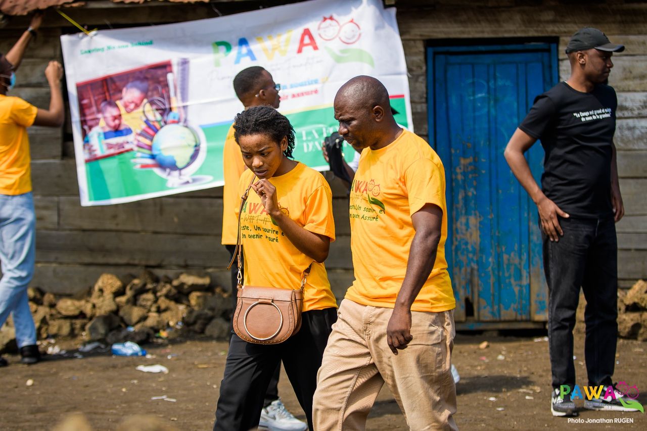 Bénévoles de l'équipe marchant devant la bannière de la campagne, à Goma