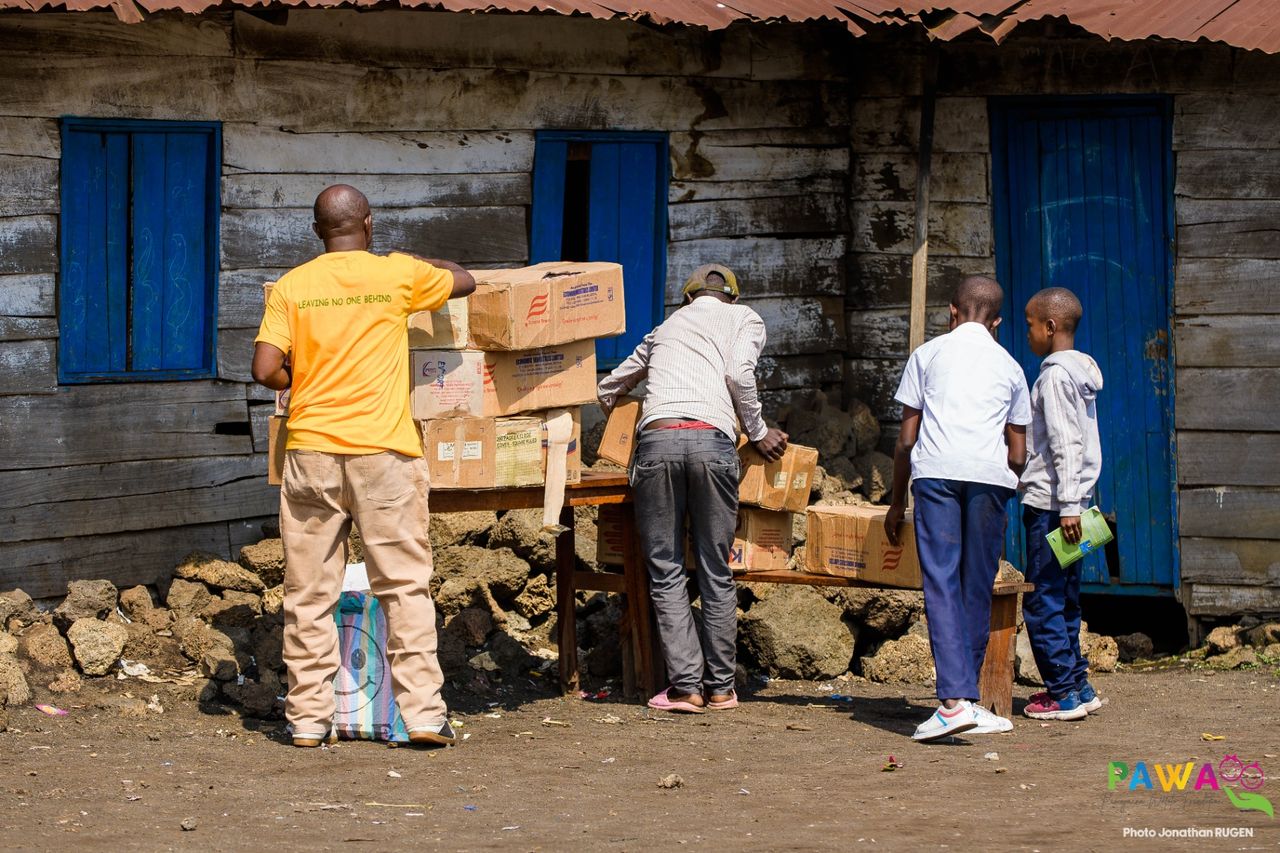 Distribution de cartons de fournitures scolaires aux familles devant une habitation, à Goma, en RDC