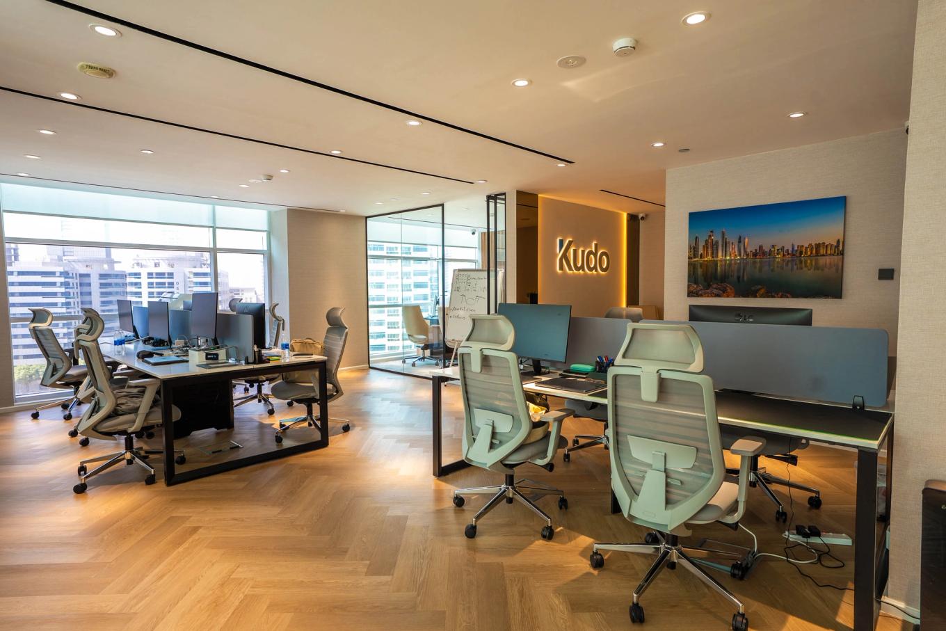 Interior of Kudo’s new Dubai office at Magnum Opus Tower, featuring modern workstations and illuminated Kudo branding.