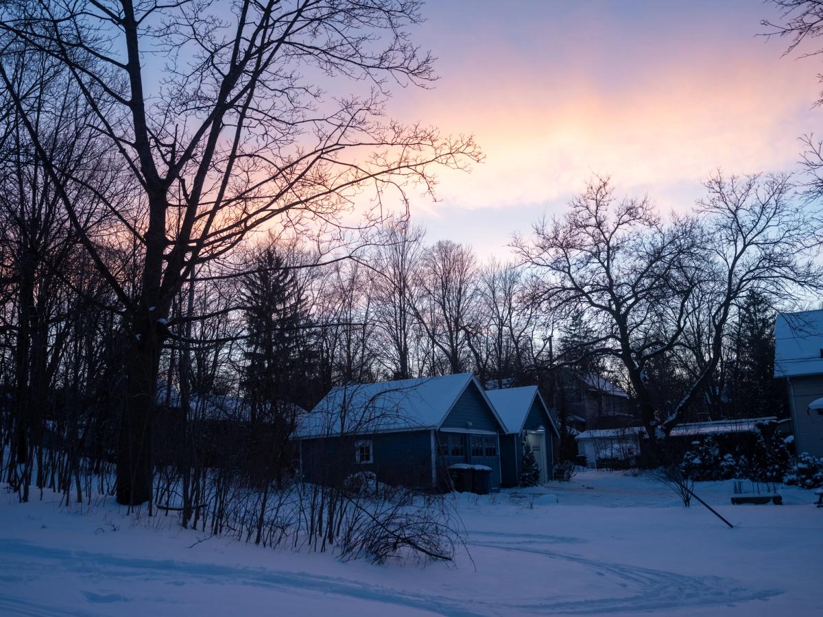 a snow covered out building of a house at dusk