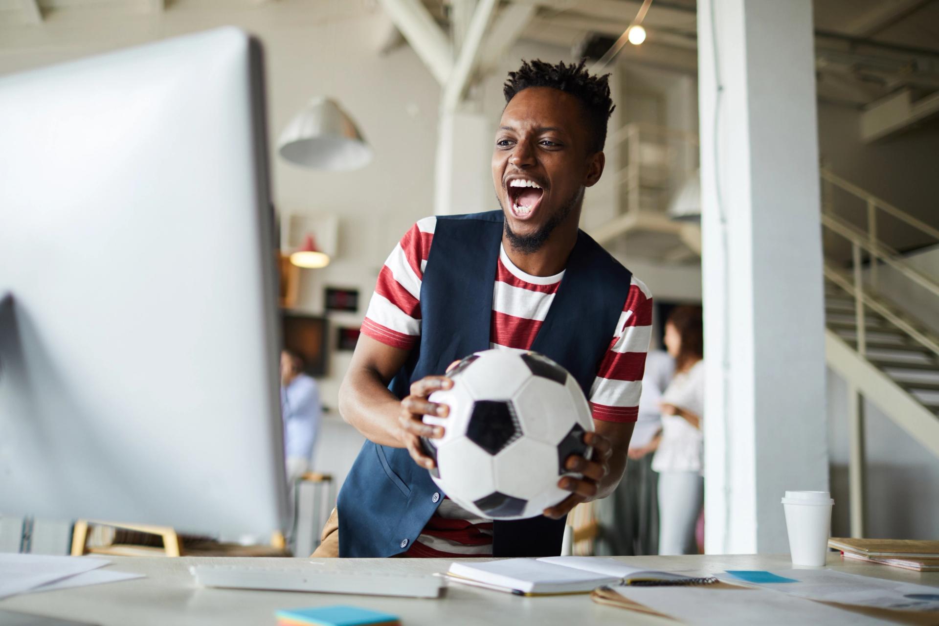 Ragazzo con pallone da calcio in mano che studia per diventare Football Manager